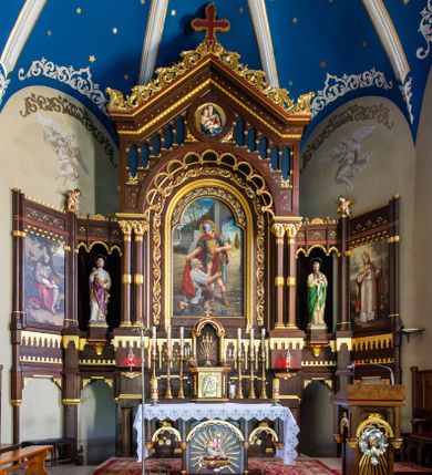 Zdjęcie nr 1: Ołtarz architektoniczny, jednokondygnacyjny, pięcioosiowy, na dwustrefowym cokole z bramkami w jego partii. Ołtarz prostopadłościenny, murowany, w drewnianej obudowie. Antepedium podzielone na trzy pola czterema pilastrami; w środkowym płaskorzeźbione serce ujęte krzyżem i kotwicą oraz kwiatami, w bocznych dekoracja roślinna. 
Tabernakulum w formie drewnianej skrzynki na planie prostokąta o ściętych przednich narożach, na profilowanym cokole, zamknięte gzymsem. Ścianka frontowa metalowa z drzwiczkami w formie stojącego prostokąta zamkniętego łukiem półkolistym z aplikowanym krzyżem z gorejącym sercem w glorii oraz winnym gronem i kłosami zbóż u spodu. Powyżej w przyłuczach aplikowana dekoracja w postaci winnego grona i kłosów zboża. Naroża i ścianki boczne dekorowane płycinami z płaskorzeźbionymi kwiatami i aplikowanymi metalowymi płytkami z kłosami zbóż. Na tabernakulum tron wystawienia w postaci baldachimu na czterech kolumienkach ze ścianką tylną z płaskorzeźbioną glorią promienistą. Baldachim o łukach ostrych, na froncie trójlistnym, z podwieszonymi wspornikami; całość zakończona krzyżem. 
Oś środkowa retabulum wyższa i szersza od pozostałych, ujęta dwiema parami stylizowanych kolumn dźwigającym archiwoltę oraz stylizowaną wimpergę, w której polu znajduje się fryz arkadkowy i medalion z płaskorzeźbioną Madonną z Dzieciątkiem (według Rafaela Santi), całość zamknięta trójkątnym gzymsem nadwieszonym, dekorowanym stylizowanym akantem, z krzyżem wieńczącym. W polu centralnym nisza w formie stojącego prostokąta zamkniętego łukiem półkolistym z wymiennymi figurami Matki Boskiej i Najświętszego Serca Jezusa, ujęta profilowaną ramą oraz pasem ornamentu roślinnego, na zasuwie wizerunek św. Marcina z Tours dzielącego się płaszczem z żebrakiem. Nisze boczne wydzielone wąskimi kolumienkami dźwigającymi niepełne belkowanie z dekoracją geometryczną i roślinną. W niszach środkowych na cokołach figury św. Piotra i św. Pawła; na osiach skrajnych malowane na desce przedstawienia św. Marcina jako mnicha po lewej stronie i św. Marcina jako biskupa po prawej. W dolnej partii strefy cokołu, na osiach wewnętrznych bramki w formie przejść; na skrajnych osiach siedziska. W partii drugiej strefy cokołu krenelaż, ornament ze stylizowanych lilii heraldycznych i płaskorzeźbiona dekoracja roślinna. Struktura w kolorze naturalnego drewna, z polichromowanymi na niebiesko i czerwono akcentami; ornamentyka i detale architektoniczne złocone.
