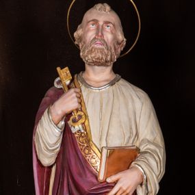 Zdjęcie nr 1: Całopostaciowa, pełnoplastyczna figura św. Piotra stojącego w kontrapoście na niewysokiej, ośmiobocznej podstawie, zwróconego na wprost. Odchyloną lekko do tyłu głowę, o wydatnych zakolach i kępkach włosów po bokach i nad czołem, charakteryzuje pociągła twarz o delikatnych rysach i krótkim, jasnobrązowym zaroście, ze wzrokiem skierowanym do góry. Święty ubrany jest w beżową suknię i przewieszony przez prawe ramię bordowy płaszcz ze złoconą bordiurą. W podniesionej i wspartej na ramieniu prawej ręce ma parę złoconych i srebrzonych kluczy, lewą podtrzymuje połę płaszcza i zamkniętą księgę w czerwonej oprawie. Głowę okala złocona aureola.   