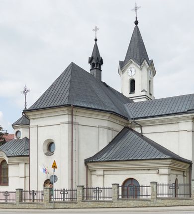 Zdjęcie nr 5: Kościół jest usytuowany pośrodku wsi Waksmund, na północ od głównej drogi z Łopusznej do Nowego Targu. Teren wokół niego jest otoczony żeliwnym płotem na kamiennej podmurówce. Na plac kościelny, od strony północno-wschodniej prowadzi murowana, otynkowana brama, nakryta dwuspadowym daszkiem z rzeźbą św. Michała Archanioła umieszczoną we wnęce nad arkadą od strony zewnętrznej.

Kościół jest orientowany. Bryłę świątyni tworzy trójnawowy korpus (przed rozbudową jednonawowy) z pseudotranseptem, węższe prezbiterium zakończone trójbocznie i wieża od zachodu. Główne wejście do świątyni prowadzi od strony zachodniej poprzez obszerną kruchtę rozbudowaną na szerokość całego kościoła z trójprzęsłową arkadą pośrodku. Osobne wejścia znajdują się od strony południowej poprzez niewielki przedsionek kaplicy oraz od strony północnej poprzez drzwi do zakrystii. Kaplica i zakrystia umieszczone są na zakończeniu naw bocznych od strony wschodniej. Wnętrze świątyni artykułowane jest masywnymi filarami, ustawionymi na styku nawy głównej z nawami bocznymi, które wspierają sklepienia krzyżowo-żebrowe. Nawę główną od prezbiterium, a także od ramion pseudotranseptu oddzielają półkoliście zakończone arkady. Na zakończeniu naw od strony zachodniej, znajdują się chóry muzyczne, głęboko wysunięte ku środkowi kościoła, z wybrzuszoną częścią środkową; w nawie głównej chór wsparty jest na parze kolumn. Nawy są oświetlone umieszczonymi w południowych i północnych ścianach prostokątnymi otworami okiennymi, zamkniętymi półkoliście (większymi na zakończeniu ramion pseudotraseptu i mniejszymi w nawach bocznych oraz w kaplicy i zakrystii). Okna w pseudotransepcie oraz jedno w kaplicy przeszklone są witrażami. Dodatkowe, pojedyncze okrągłe otwory okienne znajdują się w lukarnach oraz na ścianie wschodniej prezbiterium.

W zewnętrznej elewacji kościoła widoczny jest niewysoki, kamienny cokół, wykonany z regularnych ciosów kamienia. Elewacje ścian artykułowane są pionowymi lizenami oraz zakończone są niepełnym belkowaniem z profilowanymi gzymsami, opasującym cały budynek. Wieża jest trójkondygnacyjna, wtopiona w bryłę kościoła, na planie kwadratu. W partii drugiej kondygnacji naroża flankowane są lizenami, znajduje się tam również niewielkie okno od strony zachodniej; trzecia o ściętych narożach, a każda ze ścian przepruta jest otworami oraz dekorowana tarczami zegarowymi. 

Nawa główna z prezbiterium oraz pseduotransept nakryte są dwuspadowymi dachami z ocynkowanej blachy, a nad nawami bocznymi i kruchtą z przodu kościoła położone są dachy wielospadowe z lukarnami. Wieża nakryta jest ośmiobocznym, smukłym dachem wieżowym, zakończonym żeliwnym krzyżem, osadzonym na kuli. Nad kaplicą południową wznosi się niewielka wieżyczka z okrągłymi, małymi okienkami, nakryta ośmiospadowym niewysokim dachem wieżowym z krzyżem w zwieńczeniu, a na skrzyżowaniu nawy głównej z pseudotranseptem umieszczona jest niewielka wieżyczka na sygnaturkę, nakryta dachem wieżowym, zakończonym krzyżem.

