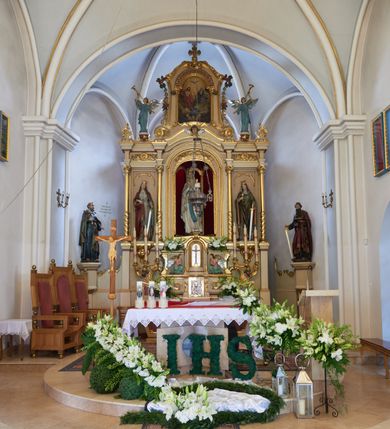 Zdjęcie nr 2: Ołtarz drewniany, zbliżony do prostopadłościanu, zwężający się ku dołowi, zakończony profilowanym gzymsem. Antependium dekorowane płycinami. Mensa drewniana. 

Tabernakulum połączone z tronem wystawienia, trójosiowe, ustawione na wysokim prostopadłościennym cokole, przed który wysunięta jest prostopadłościenna skrzynka tabernakulum. Tabernakulum ustawione na niskim, profilowanym cokole, flankowane pilastrami z płaskorzeźbionym winnym gronem, zamknięte od góry profilowanym gzymsem. Drzwiczki metalowe, groszkowane z aplikowanym kielichem z Hostią w glorii, ujęte esownicami. Tron wystawienia ustawiony nad tabernakulum w formie skrzynki zamkniętej półkoliście dwoma antytetycznymi esownicami, całość zwieńczona figurką baranka leżącego na księdze; nisza obrotowa, z jednej strony wypukła z płaskorzeźbionym przedstawieniem krucyfiksu. Tron flankują dwie ścianki stanowiące tło dla dwóch figur adorujących, czyli klęczących na cokołach aniołów. 

Nastawa ołtarzowa architektoniczna, trójosiowa z bramkami, jednokondygnacyjna ze zwieńczeniem, ustawiona na wysokim, dwustrefowym cokole. Osie wydzielone dwiema parami pilastrów i stojących przed nimi smukłych kolumn o stylizowanych kapitelach kompozytowych i skręconych trzonach na wysokości 2/5. Podpory dźwigają pełne belkowanie wyłamane na ich osi, przyjmujące nad polem środkowym kształt łuku segmentowego; na belkowaniu dwie figury aniołów dmących w trąby na ornamentalnych konsolach. W polu środkowym głęboka nisza ujęta profilowaną ramą w formie stojącego prostokąta, zamkniętego łukiem półkolistym nadwieszonym z figurą Matki Boskiej z Lourdes, na osiach bocznych na ornamentalnych konsolach figury św. Katarzyny po lewej stronie i św. Barbary po prawej stronie. Zwieńczenie w formie stojącego prostokąta zamkniętego półkoliście dwiema antytetycznie ustawionymi wolutami oraz krzyżem na szczycie; boki zwieńczenia ujęte spływami wolutowymi. W polu zwieńczenia obraz z przedstawieniem Trójcy Świętej ujęty profilowaną ramą w formie stojącego prostokąta zamkniętego łukiem półkolistym nadwieszonym oraz stylizowaną archiwoltą. Całość zamknięta dwiema wolutami z liści stylizowanego akantu oraz krzyżykiem. Bramki w formie drzwiczek na wysokości cokołu ołtarza, zamkniętych ukośnie z dekoracją ornamentalną wzdłuż brzegu. Po bokach bramek dwa cokoły wsparte na kolumnach, na których ustawione są rzeźby: św. Piotra po lewej stronie i św. Pawła po drugiej. 

Fryz dekorowany palmetami ujętymi ornamentem roślinnym; nad łukiem niszy środkowej muszla i ornament roślinny; ponad belkowaniem uskrzydlona główka anielska. Na belkowaniu, na osiach skrajnych stylizowane wazony. Zwieńczenie ujęte festonami utworzonymi z róż, kampanuli i wici roślinnej. Struktura polichromowana w kolorze beżowym, jasnoróżowymi i bordowymi akcentami; kolumny, profile i ornamentyka złocone. Po prawej stronie ołtarza sygnatura: "G(RZEGORZ) F(RANCISZEK) BEŁTOWSKI / Nowy Targ / 1909".
