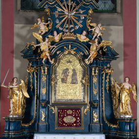 Zdjęcie nr 1: Nastawa architektoniczna, jednoosiowa, jednokondygnacyjna ze zwieńczeniem, ustawiona na wysokim cokole. Ołtarz drewniany, prostopadłościenny, o falistych bokach, mensa drewniana z marmurowym portatylem w drewnianej obudowie. Antepedium ujęte szeroką ramą dekorowaną płaskorzeźbionym motywem wieńca przepasanego wstęgą, w polu medalion z monogramem Marii ujęty wychodzącymi spod jego spodu wiązankami utworzonymi z suchego, wijącego się akantu z karbowaną wstęgą. Nastawa ujęta dwiema parami pilastrów, wewnętrzną z wolutowymi wspornikami w połowie wysokości trzonów oraz zewnętrzną parą o trzonach w formie spływów wolutowych przechodzących w silnie wysunięte do przodu partie cokołu, na których znajdują się postumenty dla figur aniołów. Podpory dźwigają niepełne belkowanie wyłamane na ich osi, nad polem środkowym wyłącznie gzyms przyjmujący kształt łuku półkolistego. Na belkowaniu fragmenty przerwanego, falistego przyczółka oraz para aniołów z kartuszami. W polu środkowym wnęka w formie stojącego prostokąta zamkniętego łukiem segmentowym nadwieszonym z uskokiem, w profilowanej ramie z mniejszym obrazem Matki Boskiej z Dzieciątkiem w kształcie stojącego prostokąta. Poniżej gablota na wota w formie leżącego prostokąta ujęta profilowaną ramą. Kondygnacja flankowana uszami utworzonymi z rocaille'u. Zwieńczenie w formie zbliżonej do kwadratu o wklęsłych bokach przechodzących w woluty, na których siedzą putta, zamknięte fragmentem falistego gzymsu wyłamanego po bokach, na nim rokokowy kartusz z monogramem IHS w polu, flankowany rocaille'em. W polu zwieńczenia rzeźba gołębicy Ducha Świętego w glorii promienistej i otoku z obłoków, w towarzystwie czterech uskrzydlonych główek anielskich. Wszystkie pilastry oraz łuki dekorowane elementami rocaille'u. Struktura w całości polichromowana na sposób imitujący marmoryzację w kolorze niebieskim, ornamentyka i profile złocone, detal srebrzony. 
Wewnątrz skrzyni ołtarzowej napisy „MALOWAŁ LUDWIK WÓJCIK Z KRAKOWA 2 / XI 1914”; „LUDWIK WÓJCIK”; „MALOWALI STOPY”; „23.02.1994 / KONSERWOWALI / KAZIMIERZ PATEJUK / EWA I JERZY SUCHWAŁKO / Z WARSZAWY / PROBOSZCZOWAŁ / KS. BOLESŁAW WAWAK”. 