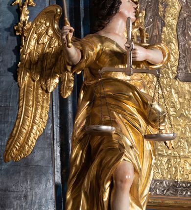 Zdjęcie nr 21: Nastawa architektoniczna, jednoosiowa, jednokondygnacyjna ze zwieńczeniem, ustawiona na wysokim cokole. Ołtarz drewniany, prostopadłościenny, o falistych bokach, mensa drewniana z marmurowym portatylem w drewnianej obudowie. Antepedium ujęte szeroką ramą dekorowaną płaskorzeźbionym motywem wieńca przepasanego wstęgą, w polu medalion z monogramem Marii ujęty wychodzącymi spod jego spodu wiązankami utworzonymi z suchego, wijącego się akantu z karbowaną wstęgą. Nastawa ujęta dwiema parami pilastrów, wewnętrzną z wolutowymi wspornikami w połowie wysokości trzonów oraz zewnętrzną parą o trzonach w formie spływów wolutowych przechodzących w silnie wysunięte do przodu partie cokołu, na których znajdują się postumenty dla figur aniołów. Podpory dźwigają niepełne belkowanie wyłamane na ich osi, nad polem środkowym wyłącznie gzyms przyjmujący kształt łuku półkolistego. Na belkowaniu fragmenty przerwanego, falistego przyczółka oraz para aniołów z kartuszami. W polu środkowym wnęka w formie stojącego prostokąta zamkniętego łukiem segmentowym nadwieszonym z uskokiem, w profilowanej ramie z mniejszym obrazem Matki Boskiej z Dzieciątkiem w kształcie stojącego prostokąta. Poniżej gablota na wota w formie leżącego prostokąta ujęta profilowaną ramą. Kondygnacja flankowana uszami utworzonymi z rocaille&#039;u. Zwieńczenie w formie zbliżonej do kwadratu o wklęsłych bokach przechodzących w woluty, na których siedzą putta, zamknięte fragmentem falistego gzymsu wyłamanego po bokach, na nim rokokowy kartusz z monogramem IHS w polu, flankowany rocaille&#039;em. W polu zwieńczenia rzeźba gołębicy Ducha Świętego w glorii promienistej i otoku z obłoków, w towarzystwie czterech uskrzydlonych główek anielskich. Wszystkie pilastry oraz łuki dekorowane elementami rocaille&#039;u. Struktura w całości polichromowana na sposób imitujący marmoryzację w kolorze niebieskim, ornamentyka i profile złocone, detal srebrzony. 
Wewnątrz skrzyni ołtarzowej napisy „MALOWAŁ LUDWIK WÓJCIK Z KRAKOWA 2 / XI 1914”; „LUDWIK WÓJCIK”; „MALOWALI STOPY”; „23.02.1994 / KONSERWOWALI / KAZIMIERZ PATEJUK / EWA I JERZY SUCHWAŁKO / Z WARSZAWY / PROBOSZCZOWAŁ / KS. BOLESŁAW WAWAK”. 