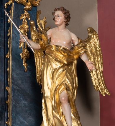 Zdjęcie nr 27: Nastawa architektoniczna, jednoosiowa, jednokondygnacyjna ze zwieńczeniem, ustawiona na wysokim cokole. Ołtarz drewniany, prostopadłościenny, o falistych bokach, mensa drewniana z marmurowym portatylem w drewnianej obudowie. Antepedium ujęte szeroką ramą dekorowaną płaskorzeźbionym motywem wieńca przepasanego wstęgą, w polu medalion z monogramem Marii ujęty wychodzącymi spod jego spodu wiązankami utworzonymi z suchego, wijącego się akantu z karbowaną wstęgą. Nastawa ujęta dwiema parami pilastrów, wewnętrzną z wolutowymi wspornikami w połowie wysokości trzonów oraz zewnętrzną parą o trzonach w formie spływów wolutowych przechodzących w silnie wysunięte do przodu partie cokołu, na których znajdują się postumenty dla figur aniołów. Podpory dźwigają niepełne belkowanie wyłamane na ich osi, nad polem środkowym wyłącznie gzyms przyjmujący kształt łuku półkolistego. Na belkowaniu fragmenty przerwanego, falistego przyczółka oraz para aniołów z kartuszami. W polu środkowym wnęka w formie stojącego prostokąta zamkniętego łukiem segmentowym nadwieszonym z uskokiem, w profilowanej ramie z mniejszym obrazem Matki Boskiej z Dzieciątkiem w kształcie stojącego prostokąta. Poniżej gablota na wota w formie leżącego prostokąta ujęta profilowaną ramą. Kondygnacja flankowana uszami utworzonymi z rocaille&#039;u. Zwieńczenie w formie zbliżonej do kwadratu o wklęsłych bokach przechodzących w woluty, na których siedzą putta, zamknięte fragmentem falistego gzymsu wyłamanego po bokach, na nim rokokowy kartusz z monogramem IHS w polu, flankowany rocaille&#039;em. W polu zwieńczenia rzeźba gołębicy Ducha Świętego w glorii promienistej i otoku z obłoków, w towarzystwie czterech uskrzydlonych główek anielskich. Wszystkie pilastry oraz łuki dekorowane elementami rocaille&#039;u. Struktura w całości polichromowana na sposób imitujący marmoryzację w kolorze niebieskim, ornamentyka i profile złocone, detal srebrzony. 
Wewnątrz skrzyni ołtarzowej napisy „MALOWAŁ LUDWIK WÓJCIK Z KRAKOWA 2 / XI 1914”; „LUDWIK WÓJCIK”; „MALOWALI STOPY”; „23.02.1994 / KONSERWOWALI / KAZIMIERZ PATEJUK / EWA I JERZY SUCHWAŁKO / Z WARSZAWY / PROBOSZCZOWAŁ / KS. BOLESŁAW WAWAK”. 