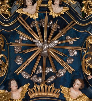 Zdjęcie nr 14: Nastawa architektoniczna, jednoosiowa, jednokondygnacyjna ze zwieńczeniem, ustawiona na wysokim cokole. Ołtarz drewniany, prostopadłościenny, o falistych bokach, mensa drewniana z marmurowym portatylem w drewnianej obudowie. Antepedium ujęte szeroką ramą dekorowaną płaskorzeźbionym motywem wieńca przepasanego wstęgą, w polu medalion z monogramem Marii ujęty wychodzącymi spod jego spodu wiązankami utworzonymi z suchego, wijącego się akantu z karbowaną wstęgą. Nastawa ujęta dwiema parami pilastrów, wewnętrzną z wolutowymi wspornikami w połowie wysokości trzonów oraz zewnętrzną parą o trzonach w formie spływów wolutowych przechodzących w silnie wysunięte do przodu partie cokołu, na których znajdują się postumenty dla figur aniołów. Podpory dźwigają niepełne belkowanie wyłamane na ich osi, nad polem środkowym wyłącznie gzyms przyjmujący kształt łuku półkolistego. Na belkowaniu fragmenty przerwanego, falistego przyczółka oraz para aniołów z kartuszami. W polu środkowym wnęka w formie stojącego prostokąta zamkniętego łukiem segmentowym nadwieszonym z uskokiem, w profilowanej ramie z mniejszym obrazem Matki Boskiej z Dzieciątkiem w kształcie stojącego prostokąta. Poniżej gablota na wota w formie leżącego prostokąta ujęta profilowaną ramą. Kondygnacja flankowana uszami utworzonymi z rocaille'u. Zwieńczenie w formie zbliżonej do kwadratu o wklęsłych bokach przechodzących w woluty, na których siedzą putta, zamknięte fragmentem falistego gzymsu wyłamanego po bokach, na nim rokokowy kartusz z monogramem IHS w polu, flankowany rocaille'em. W polu zwieńczenia rzeźba gołębicy Ducha Świętego w glorii promienistej i otoku z obłoków, w towarzystwie czterech uskrzydlonych główek anielskich. Wszystkie pilastry oraz łuki dekorowane elementami rocaille'u. Struktura w całości polichromowana na sposób imitujący marmoryzację w kolorze niebieskim, ornamentyka i profile złocone, detal srebrzony. 
Wewnątrz skrzyni ołtarzowej napisy „MALOWAŁ LUDWIK WÓJCIK Z KRAKOWA 2 / XI 1914”; „LUDWIK WÓJCIK”; „MALOWALI STOPY”; „23.02.1994 / KONSERWOWALI / KAZIMIERZ PATEJUK / EWA I JERZY SUCHWAŁKO / Z WARSZAWY / PROBOSZCZOWAŁ / KS. BOLESŁAW WAWAK”. 