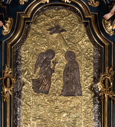 Zdjęcie nr 30: Nastawa architektoniczna, jednoosiowa, jednokondygnacyjna ze zwieńczeniem, ustawiona na wysokim cokole. Ołtarz drewniany, prostopadłościenny, o falistych bokach, mensa drewniana z marmurowym portatylem w drewnianej obudowie. Antepedium ujęte szeroką ramą dekorowaną płaskorzeźbionym motywem wieńca przepasanego wstęgą, w polu medalion z monogramem Marii ujęty wychodzącymi spod jego spodu wiązankami utworzonymi z suchego, wijącego się akantu z karbowaną wstęgą. Nastawa ujęta dwiema parami pilastrów, wewnętrzną z wolutowymi wspornikami w połowie wysokości trzonów oraz zewnętrzną parą o trzonach w formie spływów wolutowych przechodzących w silnie wysunięte do przodu partie cokołu, na których znajdują się postumenty dla figur aniołów. Podpory dźwigają niepełne belkowanie wyłamane na ich osi, nad polem środkowym wyłącznie gzyms przyjmujący kształt łuku półkolistego. Na belkowaniu fragmenty przerwanego, falistego przyczółka oraz para aniołów z kartuszami. W polu środkowym wnęka w formie stojącego prostokąta zamkniętego łukiem segmentowym nadwieszonym z uskokiem, w profilowanej ramie z mniejszym obrazem Matki Boskiej z Dzieciątkiem w kształcie stojącego prostokąta. Poniżej gablota na wota w formie leżącego prostokąta ujęta profilowaną ramą. Kondygnacja flankowana uszami utworzonymi z rocaille&#039;u. Zwieńczenie w formie zbliżonej do kwadratu o wklęsłych bokach przechodzących w woluty, na których siedzą putta, zamknięte fragmentem falistego gzymsu wyłamanego po bokach, na nim rokokowy kartusz z monogramem IHS w polu, flankowany rocaille&#039;em. W polu zwieńczenia rzeźba gołębicy Ducha Świętego w glorii promienistej i otoku z obłoków, w towarzystwie czterech uskrzydlonych główek anielskich. Wszystkie pilastry oraz łuki dekorowane elementami rocaille&#039;u. Struktura w całości polichromowana na sposób imitujący marmoryzację w kolorze niebieskim, ornamentyka i profile złocone, detal srebrzony. 
Wewnątrz skrzyni ołtarzowej napisy „MALOWAŁ LUDWIK WÓJCIK Z KRAKOWA 2 / XI 1914”; „LUDWIK WÓJCIK”; „MALOWALI STOPY”; „23.02.1994 / KONSERWOWALI / KAZIMIERZ PATEJUK / EWA I JERZY SUCHWAŁKO / Z WARSZAWY / PROBOSZCZOWAŁ / KS. BOLESŁAW WAWAK”. 