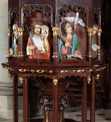 Zdjęcie nr 1: Ambona wolnostojąca, ustawiona na ośmiobocznej, dwustopniowej podstawie oraz środkowej kolumnie dekorowanej liśćmi akantu i otaczającymi ją ośmioma kolumienkami. Kosz na planie ośmioboku, na niewielkiej podstawie z podwieszonymi kwiatonami, z dostępem w postaci jednobiegowych schodów z dwiema balustradami dekorowanymi stylizowanymi blendami. Ścianki kosza wydzielone niskimi kolumienkami. W polach prostokątne nisze w formie stojącego prostokąta, w górnej partii dekorowane stylizowanym astwerkiem, z płaskorzeźbionymi czterech ewangelistów i Chrystusa Dobrego Pasterza. Parapet w formie gzymsu z pulpitem. Struktura politurowana w kolorze ciemnego brązu, detal złocony, wizerunki postaci polichromowane. Płaskorzeźby Chrystusa i ewangelistów ukazane w półpostaci. Apostołowie zwróceni są w trzech czwartych, w dłoniach trzymają pióra i zwoje lub księgi, towarzyszą im ich symbole. Chrystus lewą ręką podtrzymuje na ramieniu owcę, w prawej trzyma laskę pasterską. Wszyscy ubrani są w obszerne tuniki i płaszcze narzucone na ramiona. 