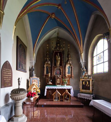 Zdjęcie nr 2: Nastawa ołtarzowa architektoniczna, trójosiowa, jednokondygnacyjna, z predellą. Ołtarz drewniany prostopadłościenny, z drewnianą mensą i portatylem z marmuru dębnickiego. W polu antepedium płycina ujęta blendami i maswerkiem; w centrum monogram Marii w wieńcu róż. Tabernakulum w formie prostopadłościennej skrzynki zamkniętej krenelażem, ujęte dwiema kolumienkami z pinaklami, z prostokątnymi drzwiczkami zamkniętymi łukiem ostrym z płaskorzeźbionym przedstawieniem kielicha, hostią w glorii, winną latoroślą i kłosami zbóż. Osie nastawy wydzielone smukłymi półkolumnami, zakończonymi pinaklami z kwiatonami. Oś środkowa dwukrotnie wyższa i szersza od bocznych. W polu środkowym nisza w formie stojącego prostokąta z figurą Matki Boskiej z Dzieciątkiem. Wnęka ujęta ramą dekorowaną ornamentem roślinnym. Poniżej płycina w kształcie kwadratu zamkniętego łukiem segmentowym, ujęta maswerkową ramą z przedstawieniem Chrystusa z więźniami obozu koncentracyjnego i duchownymi. Oś główna zamknięta baldachimem utworzonym z trzech wimperg oraz szczytem z pinakli i kwiatonów. Osie boczne z wnękami z obrazami bł. Stanisława Pyrtka i bł. Piotra Dańkowskiego, zwieńczonymi baldachimami utworzonymi z trzech wimperg i zakończonymi gotyckimi wieżyczkami. Struktura nastawy politurowana w kolorze jasnobrązowym, ornamentyka i detale architektoniczne złocone. 

