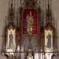 Zdjęcie nr 1: Nastawa ołtarzowa architektoniczna, trójosiowa, jednokondygnacyjna, z predellą. Ołtarz drewniany prostopadłościenny, z drewnianą mensą i portatylem z marmuru dębnickiego. W polu antepedium płycina ujęta blendami i maswerkiem; w centrum monogram Marii w wieńcu róż. Tabernakulum w formie prostopadłościennej skrzynki zamkniętej krenelażem, ujęte dwiema kolumienkami z pinaklami, z prostokątnymi drzwiczkami zamkniętymi łukiem ostrym z płaskorzeźbionym przedstawieniem kielicha, hostią w glorii, winną latoroślą i kłosami zbóż. Osie nastawy wydzielone smukłymi półkolumnami, zakończonymi pinaklami z kwiatonami. Oś środkowa dwukrotnie wyższa i szersza od bocznych. W polu środkowym nisza w formie stojącego prostokąta z figurą Matki Boskiej z Dzieciątkiem. Wnęka ujęta ramą dekorowaną ornamentem roślinnym. Poniżej płycina w kształcie kwadratu zamkniętego łukiem segmentowym, ujęta maswerkową ramą z przedstawieniem Chrystusa z więźniami obozu koncentracyjnego i duchownymi. Oś główna zamknięta baldachimem utworzonym z trzech wimperg oraz szczytem z pinakli i kwiatonów. Osie boczne z wnękami z obrazami bł. Stanisława Pyrtka i bł. Piotra Dańkowskiego, zwieńczonymi baldachimami utworzonymi z trzech wimperg i zakończonymi gotyckimi wieżyczkami. Struktura nastawy politurowana w kolorze jasnobrązowym, ornamentyka i detale architektoniczne złocone. 

