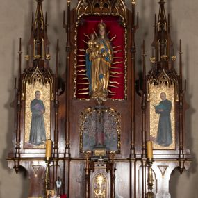 Zdjęcie nr 1: Nastawa ołtarzowa architektoniczna, trójosiowa, jednokondygnacyjna, z predellą. Ołtarz drewniany prostopadłościenny, z drewnianą mensą i portatylem z marmuru dębnickiego. W polu antepedium płycina ujęta blendami i maswerkiem; w centrum monogram Marii w wieńcu róż. Tabernakulum w formie prostopadłościennej skrzynki zamkniętej krenelażem, ujęte dwiema kolumienkami z pinaklami, z prostokątnymi drzwiczkami zamkniętymi łukiem ostrym z płaskorzeźbionym przedstawieniem kielicha, hostią w glorii, winną latoroślą i kłosami zbóż. Osie nastawy wydzielone smukłymi półkolumnami, zakończonymi pinaklami z kwiatonami. Oś środkowa dwukrotnie wyższa i szersza od bocznych. W polu środkowym nisza w formie stojącego prostokąta z figurą Matki Boskiej z Dzieciątkiem. Wnęka ujęta ramą dekorowaną ornamentem roślinnym. Poniżej płycina w kształcie kwadratu zamkniętego łukiem segmentowym, ujęta maswerkową ramą z przedstawieniem Chrystusa z więźniami obozu koncentracyjnego i duchownymi. Oś główna zamknięta baldachimem utworzonym z trzech wimperg oraz szczytem z pinakli i kwiatonów. Osie boczne z wnękami z obrazami bł. Stanisława Pyrtka i bł. Piotra Dańkowskiego, zwieńczonymi baldachimami utworzonymi z trzech wimperg i zakończonymi gotyckimi wieżyczkami. Struktura nastawy politurowana w kolorze jasnobrązowym, ornamentyka i detale architektoniczne złocone. 

