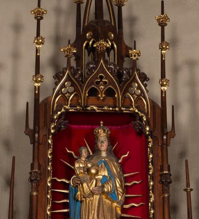 Zdjęcie nr 10: Nastawa ołtarzowa architektoniczna, trójosiowa, jednokondygnacyjna, z predellą. Ołtarz drewniany prostopadłościenny, z drewnianą mensą i portatylem z marmuru dębnickiego. W polu antepedium płycina ujęta blendami i maswerkiem; w centrum monogram Marii w wieńcu róż. Tabernakulum w formie prostopadłościennej skrzynki zamkniętej krenelażem, ujęte dwiema kolumienkami z pinaklami, z prostokątnymi drzwiczkami zamkniętymi łukiem ostrym z płaskorzeźbionym przedstawieniem kielicha, hostią w glorii, winną latoroślą i kłosami zbóż. Osie nastawy wydzielone smukłymi półkolumnami, zakończonymi pinaklami z kwiatonami. Oś środkowa dwukrotnie wyższa i szersza od bocznych. W polu środkowym nisza w formie stojącego prostokąta z figurą Matki Boskiej z Dzieciątkiem. Wnęka ujęta ramą dekorowaną ornamentem roślinnym. Poniżej płycina w kształcie kwadratu zamkniętego łukiem segmentowym, ujęta maswerkową ramą z przedstawieniem Chrystusa z więźniami obozu koncentracyjnego i duchownymi. Oś główna zamknięta baldachimem utworzonym z trzech wimperg oraz szczytem z pinakli i kwiatonów. Osie boczne z wnękami z obrazami bł. Stanisława Pyrtka i bł. Piotra Dańkowskiego, zwieńczonymi baldachimami utworzonymi z trzech wimperg i zakończonymi gotyckimi wieżyczkami. Struktura nastawy politurowana w kolorze jasnobrązowym, ornamentyka i detale architektoniczne złocone. 

