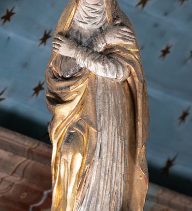 Zdjęcie nr 15: Belka tęczowa o falistym zarysie, zwieńczona profilowanym gzymsem. Z przodu napis „WSZYSCY KTÓRZY PRZYCHO/DZICIE OBACZCIE I UWAŻCIE: / OCZY MOJE BĘDĄ OTWARTE I USZY NACHYLONE NA PROŚBĘ TEGO KTÓRY SIĘ NA TEM MIEJSCU MODLIĆ BĘDZIE.”, na odwrociu napis „TEN KOŚCIÓŁ FUNDOWANY/ PRZEZ BARBARĘ LISICKĄ. / KONSEKROWANY W ROKU 1766. / ODNOMIONY W ROKU 1902. PO RAZ DRUGI W 1980”. Na belce ustawione figury ze sceny Ukrzyżowania. Pośrodku krzyż, do którego przybita jest trzema gwoździami figura umarłego Chrystusa. Ciało w lekkim zwisie o horyzontalnie rozłożonych ramionach, z głową opadającą na prawe ramię, z lekko ugiętymi nogami oraz stopami skrzyżowanymi w układzie prawa na lewą. Twarz ma szczupłą, o zamkniętych oczach, uniesionych brwiach, dużym, wąskim nosie oraz otwartych ustach, okoloną krótką, falowaną brodą i silnie kręconymi włosami opadającymi na ramiona. Na głowie ma koronę cierniową. Ciało jest wychudzone, o silnie zaznaczonych, guzowatych żebrach klatki piersiowej oraz mięśniach i ścięgnach ramion i ud. W partii bioder złocone perizonium zawieszone na sznurze, odsłaniające prawe udo, zawiązane ze zwisem tkaniny na prawym biodrze. 
U dołu krzyża klęczy Maria Magdalena, zwrócona w trzech czwartych w lewo, z uniesioną głową, obiema rękami obejmuje belkę. Twarz ma pociągłą, o małych oczach, krótkim nosie i wąskich ustach, okoloną długimi falowanymi włosami opadającymi na ramiona. Ubrana jest w srebrzoną suknię oraz złocony płaszcz. 
Po prawej stronie krzyża figura Marii, zwrócona w trzech czwartych w lewo, w kontrapoście, z pochyloną głową i rękami skrzyżowanymi na piersi. Twarz ma pociągłą, o wąskich oczach, uniesionych brwiach, małych nosie i ustach. Ubrana jest w srebrzoną suknię oraz złocony płaszcz narzucony na głowę i ramiona, wokół głowy ma białą podwikę. 
Po lewej stronie krzyża św. Jan zwrócony w trzech czwartych w prawo, w kontrapoście, prawą rękę kładzie na piersi, w lewej, opuszczonej trzyma księgę. Twarz ma pociągłą, o wąskich oczach, małych nosie i ustach, okoloną brązowymi, silnie kręconymi włosami, sięgającymi ramion, z czubem nad czołem. Ubrany jest w srebrzoną tunikę z kołnierzykiem, przepasaną w talii oraz złocony płaszcz zarzucony na prawe ramię i podtrzymywany na lewym boku. Polichromia ciał postaci naturalistyczna. 