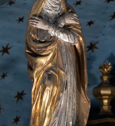 Zdjęcie nr 16: Belka tęczowa o falistym zarysie, zwieńczona profilowanym gzymsem. Z przodu napis „WSZYSCY KTÓRZY PRZYCHO/DZICIE OBACZCIE I UWAŻCIE: / OCZY MOJE BĘDĄ OTWARTE I USZY NACHYLONE NA PROŚBĘ TEGO KTÓRY SIĘ NA TEM MIEJSCU MODLIĆ BĘDZIE.”, na odwrociu napis „TEN KOŚCIÓŁ FUNDOWANY/ PRZEZ BARBARĘ LISICKĄ. / KONSEKROWANY W ROKU 1766. / ODNOMIONY W ROKU 1902. PO RAZ DRUGI W 1980”. Na belce ustawione figury ze sceny Ukrzyżowania. Pośrodku krzyż, do którego przybita jest trzema gwoździami figura umarłego Chrystusa. Ciało w lekkim zwisie o horyzontalnie rozłożonych ramionach, z głową opadającą na prawe ramię, z lekko ugiętymi nogami oraz stopami skrzyżowanymi w układzie prawa na lewą. Twarz ma szczupłą, o zamkniętych oczach, uniesionych brwiach, dużym, wąskim nosie oraz otwartych ustach, okoloną krótką, falowaną brodą i silnie kręconymi włosami opadającymi na ramiona. Na głowie ma koronę cierniową. Ciało jest wychudzone, o silnie zaznaczonych, guzowatych żebrach klatki piersiowej oraz mięśniach i ścięgnach ramion i ud. W partii bioder złocone perizonium zawieszone na sznurze, odsłaniające prawe udo, zawiązane ze zwisem tkaniny na prawym biodrze. 
U dołu krzyża klęczy Maria Magdalena, zwrócona w trzech czwartych w lewo, z uniesioną głową, obiema rękami obejmuje belkę. Twarz ma pociągłą, o małych oczach, krótkim nosie i wąskich ustach, okoloną długimi falowanymi włosami opadającymi na ramiona. Ubrana jest w srebrzoną suknię oraz złocony płaszcz. 
Po prawej stronie krzyża figura Marii, zwrócona w trzech czwartych w lewo, w kontrapoście, z pochyloną głową i rękami skrzyżowanymi na piersi. Twarz ma pociągłą, o wąskich oczach, uniesionych brwiach, małych nosie i ustach. Ubrana jest w srebrzoną suknię oraz złocony płaszcz narzucony na głowę i ramiona, wokół głowy ma białą podwikę. 
Po lewej stronie krzyża św. Jan zwrócony w trzech czwartych w prawo, w kontrapoście, prawą rękę kładzie na piersi, w lewej, opuszczonej trzyma księgę. Twarz ma pociągłą, o wąskich oczach, małych nosie i ustach, okoloną brązowymi, silnie kręconymi włosami, sięgającymi ramion, z czubem nad czołem. Ubrany jest w srebrzoną tunikę z kołnierzykiem, przepasaną w talii oraz złocony płaszcz zarzucony na prawe ramię i podtrzymywany na lewym boku. Polichromia ciał postaci naturalistyczna. 