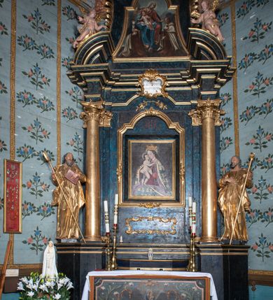 Zdjęcie nr 2: Nastawa architektoniczna, jednoosiowa, jednokondygnacyjna ze zwieńczeniem. Ołtarz prostopadłościenny, murowany, w drewnianej obudowie, z kamienną mensą. 
Antepedium ujęte profilowaną ramą, w polu malowana płycina w formie leżącego prostokąta o wklęsłych narożach, wypełniona wicią roślinną z różami, z kartuszem w centrum. W narożach przedstawienia ptaków na gałęziach. W polu kartusza ukazana półpostać Matki Boskiej Szkaplerznej unoszącej się nad duszami czyśćcowymi, na tle nieba. Retabulum ustawione na wysokim cokole, szerszym od nastawy, z wyłamanymi czterema prostopadłościanami. Nastawa ujęta parą zdwojonych pilastrów i parą stojących przed nimi kolumn o kapitelach kompozytowych, dźwigających pełne belkowanie, wyłamane na ich osi, z architrawem przyjmującym nad polem środkowym formę łuku odcinkowego. Na belkowaniu fragmenty półkolistego, przerwanego przyczółka z siedzącymi puttami. W polu centralnym wnęka w formie stojącego prostokąta zamkniętego łukiem półkolistym nadwieszonym z uskokiem, ujęta profilowaną ramą, z mniejszym obrazem Matki Boskiej z Dzieciątkiem w kształcie stojącego prostokąta. Powyżej, w podłuczu monogram Marii. Nad wnęką, w polu belkowania rocaille'owy kartusz z napisem „SANCTA MARIA / ORA PRO NOBIS”. Na skrajnych partiach cokołu ustawione figury św. Joachima i św. Józefa. Zwieńczenie w formie zbliżonej do trapezu, ujętego spływami wolutowymi, zamkniętego fragmentem gzymsu w formie łuku półkolistego nadwieszonego. Flankowane liśćmi palmowymi, gzyms dekorowany rocaille'm. W polu obraz Matki Boskiej Szkaplerznej ze św. Szymonem Stockiem i św. Teresą z Avili w formie analogicznej do zwieńczenia, w profilowanej ramie. Struktura polichromowana na sposób imitujący marmoryzację w kolorze niebiesko-czarnym, profile i ornamentyka złocone, detal srebrzony. 


