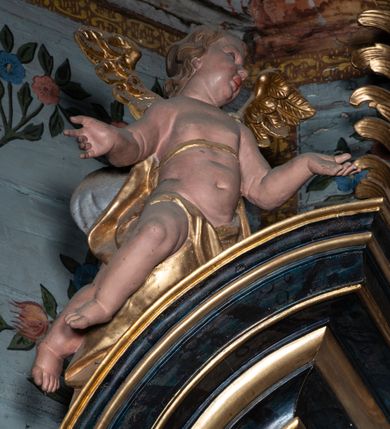 Zdjęcie nr 30: Nastawa architektoniczna, jednoosiowa, jednokondygnacyjna ze zwieńczeniem. Ołtarz prostopadłościenny, murowany, w drewnianej obudowie, z kamienną mensą. 
Antepedium ujęte profilowaną ramą, w polu malowana płycina w formie leżącego prostokąta o wklęsłych narożach, wypełniona wicią roślinną z różami, z kartuszem w centrum. W narożach przedstawienia ptaków na gałęziach. W polu kartusza ukazana półpostać Matki Boskiej Szkaplerznej unoszącej się nad duszami czyśćcowymi, na tle nieba. Retabulum ustawione na wysokim cokole, szerszym od nastawy, z wyłamanymi czterema prostopadłościanami. Nastawa ujęta parą zdwojonych pilastrów i parą stojących przed nimi kolumn o kapitelach kompozytowych, dźwigających pełne belkowanie, wyłamane na ich osi, z architrawem przyjmującym nad polem środkowym formę łuku odcinkowego. Na belkowaniu fragmenty półkolistego, przerwanego przyczółka z siedzącymi puttami. W polu centralnym wnęka w formie stojącego prostokąta zamkniętego łukiem półkolistym nadwieszonym z uskokiem, ujęta profilowaną ramą, z mniejszym obrazem Matki Boskiej z Dzieciątkiem w kształcie stojącego prostokąta. Powyżej, w podłuczu monogram Marii. Nad wnęką, w polu belkowania rocaille'owy kartusz z napisem „SANCTA MARIA / ORA PRO NOBIS”. Na skrajnych partiach cokołu ustawione figury św. Joachima i św. Józefa. Zwieńczenie w formie zbliżonej do trapezu, ujętego spływami wolutowymi, zamkniętego fragmentem gzymsu w formie łuku półkolistego nadwieszonego. Flankowane liśćmi palmowymi, gzyms dekorowany rocaille'm. W polu obraz Matki Boskiej Szkaplerznej ze św. Szymonem Stockiem i św. Teresą z Avili w formie analogicznej do zwieńczenia, w profilowanej ramie. Struktura polichromowana na sposób imitujący marmoryzację w kolorze niebiesko-czarnym, profile i ornamentyka złocone, detal srebrzony. 


