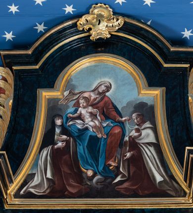 Zdjęcie nr 18: Nastawa architektoniczna, jednoosiowa, jednokondygnacyjna ze zwieńczeniem. Ołtarz prostopadłościenny, murowany, w drewnianej obudowie, z kamienną mensą. 
Antepedium ujęte profilowaną ramą, w polu malowana płycina w formie leżącego prostokąta o wklęsłych narożach, wypełniona wicią roślinną z różami, z kartuszem w centrum. W narożach przedstawienia ptaków na gałęziach. W polu kartusza ukazana półpostać Matki Boskiej Szkaplerznej unoszącej się nad duszami czyśćcowymi, na tle nieba. Retabulum ustawione na wysokim cokole, szerszym od nastawy, z wyłamanymi czterema prostopadłościanami. Nastawa ujęta parą zdwojonych pilastrów i parą stojących przed nimi kolumn o kapitelach kompozytowych, dźwigających pełne belkowanie, wyłamane na ich osi, z architrawem przyjmującym nad polem środkowym formę łuku odcinkowego. Na belkowaniu fragmenty półkolistego, przerwanego przyczółka z siedzącymi puttami. W polu centralnym wnęka w formie stojącego prostokąta zamkniętego łukiem półkolistym nadwieszonym z uskokiem, ujęta profilowaną ramą, z mniejszym obrazem Matki Boskiej z Dzieciątkiem w kształcie stojącego prostokąta. Powyżej, w podłuczu monogram Marii. Nad wnęką, w polu belkowania rocaille'owy kartusz z napisem „SANCTA MARIA / ORA PRO NOBIS”. Na skrajnych partiach cokołu ustawione figury św. Joachima i św. Józefa. Zwieńczenie w formie zbliżonej do trapezu, ujętego spływami wolutowymi, zamkniętego fragmentem gzymsu w formie łuku półkolistego nadwieszonego. Flankowane liśćmi palmowymi, gzyms dekorowany rocaille'm. W polu obraz Matki Boskiej Szkaplerznej ze św. Szymonem Stockiem i św. Teresą z Avili w formie analogicznej do zwieńczenia, w profilowanej ramie. Struktura polichromowana na sposób imitujący marmoryzację w kolorze niebiesko-czarnym, profile i ornamentyka złocone, detal srebrzony. 


