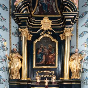 Zdjęcie nr 1: Nastawa architektoniczna, jednoosiowa, jednokondygnacyjna ze zwieńczeniem. Ołtarz prostopadłościenny, murowany, w drewnianej obudowie, z kamienną mensą. 
Antepedium ujęte profilowaną ramą, w polu malowana płycina w formie leżącego prostokąta o wklęsłych narożach, wypełniona wicią roślinną z różami, z kartuszem w centrum. W narożach przedstawienia ptaków na gałęziach. W polu kartusza ukazana półpostać Matki Boskiej Szkaplerznej unoszącej się nad duszami czyśćcowymi, na tle nieba. Retabulum ustawione na wysokim cokole, szerszym od nastawy, z wyłamanymi czterema prostopadłościanami. Nastawa ujęta parą zdwojonych pilastrów i parą stojących przed nimi kolumn o kapitelach kompozytowych, dźwigających pełne belkowanie, wyłamane na ich osi, z architrawem przyjmującym nad polem środkowym formę łuku odcinkowego. Na belkowaniu fragmenty półkolistego, przerwanego przyczółka z siedzącymi puttami. W polu centralnym wnęka w formie stojącego prostokąta zamkniętego łukiem półkolistym nadwieszonym z uskokiem, ujęta profilowaną ramą, z mniejszym obrazem Matki Boskiej z Dzieciątkiem w kształcie stojącego prostokąta. Powyżej, w podłuczu monogram Marii. Nad wnęką, w polu belkowania rocaille'owy kartusz z napisem „SANCTA MARIA / ORA PRO NOBIS”. Na skrajnych partiach cokołu ustawione figury św. Joachima i św. Józefa. Zwieńczenie w formie zbliżonej do trapezu, ujętego spływami wolutowymi, zamkniętego fragmentem gzymsu w formie łuku półkolistego nadwieszonego. Flankowane liśćmi palmowymi, gzyms dekorowany rocaille'm. W polu obraz Matki Boskiej Szkaplerznej ze św. Szymonem Stockiem i św. Teresą z Avili w formie analogicznej do zwieńczenia, w profilowanej ramie. Struktura polichromowana na sposób imitujący marmoryzację w kolorze niebiesko-czarnym, profile i ornamentyka złocone, detal srebrzony. 


