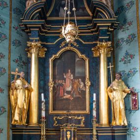 Zdjęcie nr 1: Nastawa architektoniczna, jednoosiowa, jednokondygnacyjna ze zwieńczeniem. Ołtarz prostopadłościenny, murowany, w drewnianej obudowie, z kamienną mensą. 
Antepedium ujęte profilowaną ramą, w polu malowana płycina w formie leżącego prostokąta o wklęsłych narożach, wypełniona wicią roślinną z różami, z kartuszem w centrum. W narożach przedstawienia ptaków na gałęziach. W polu kartusza scena męczeństwa św. Walentego, na tle pejzażu. Retabulum ustawione na wysokim cokole, szerszym od nastawy, z wyłamanymi czterema prostopadłościanami. Nastawa ujęta parą zdwojonych pilastrów i parą stojących przed nimi kolumn o kapitelach kompozytowych, dźwigających pełne belkowanie, wyłamane na ich osi, z architrawem przyjmującym nad polem środkowym formę łuku odcinkowego. Na belkowaniu fragmenty półkolistego, przerwanego przyczółka z siedzącymi puttami. W polu centralnym wnęka w formie stojącego prostokąta zamkniętego łukiem półkolistym nadwieszonym z uskokiem, ujęta profilowaną ramą, z obrazem św. Walentego. Nad nią, w polu belkowania rocaille'owy kartusz z napisem „GLORIA HONORE / CORONASTI EUM / DOMINE”. Na skrajnych partiach cokołu ustawione figury św. Jana od Krzyża i św. Jana Kapistrana (?). Zwieńczenie w formie zbliżonej do trapezu, ujętego spływami wolutowymi, zamkniętego fragmentem gzymsu w formie łuku półkolistego nadwieszonego. Zwieńczenie flankowane liśćmi palmowymi, gzyms dekorowany rocaille'm. W polu obraz św. Jana Nepomucena w kształcie analogicznym do zwieńczenia, w profilowanej ramie. Struktura polichromowana na sposób imitujący marmoryzację w kolorze niebieskim, profile i ornamentyka złocone, detal srebrzony. 

