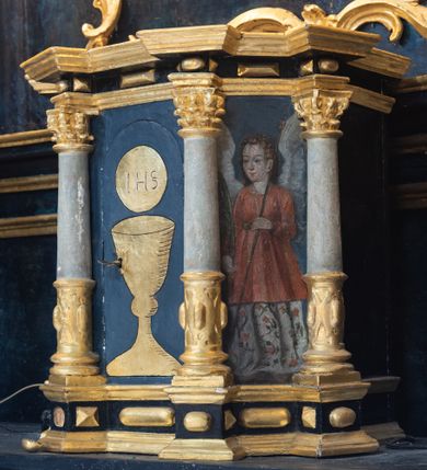 Zdjęcie nr 19: Nastawa architektoniczna, jednoosiowa, jednokondygnacyjna ze zwieńczeniem. Ołtarz prostopadłościenny, murowany, w drewnianej obudowie, z kamienną mensą. 
Antepedium ujęte profilowaną ramą, w polu malowana płycina w formie leżącego prostokąta o wklęsłych narożach, wypełniona wicią roślinną z różami, z kartuszem w centrum. W narożach przedstawienia ptaków na gałęziach. W polu kartusza scena męczeństwa św. Walentego, na tle pejzażu. Retabulum ustawione na wysokim cokole, szerszym od nastawy, z wyłamanymi czterema prostopadłościanami. Nastawa ujęta parą zdwojonych pilastrów i parą stojących przed nimi kolumn o kapitelach kompozytowych, dźwigających pełne belkowanie, wyłamane na ich osi, z architrawem przyjmującym nad polem środkowym formę łuku odcinkowego. Na belkowaniu fragmenty półkolistego, przerwanego przyczółka z siedzącymi puttami. W polu centralnym wnęka w formie stojącego prostokąta zamkniętego łukiem półkolistym nadwieszonym z uskokiem, ujęta profilowaną ramą, z obrazem św. Walentego. Nad nią, w polu belkowania rocaille'owy kartusz z napisem „GLORIA HONORE / CORONASTI EUM / DOMINE”. Na skrajnych partiach cokołu ustawione figury św. Jana od Krzyża i św. Jana Kapistrana (?). Zwieńczenie w formie zbliżonej do trapezu, ujętego spływami wolutowymi, zamkniętego fragmentem gzymsu w formie łuku półkolistego nadwieszonego. Zwieńczenie flankowane liśćmi palmowymi, gzyms dekorowany rocaille'm. W polu obraz św. Jana Nepomucena w kształcie analogicznym do zwieńczenia, w profilowanej ramie. Struktura polichromowana na sposób imitujący marmoryzację w kolorze niebieskim, profile i ornamentyka złocone, detal srebrzony. 

