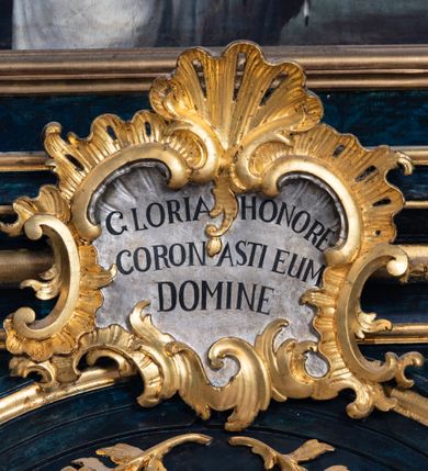 Zdjęcie nr 15: Nastawa architektoniczna, jednoosiowa, jednokondygnacyjna ze zwieńczeniem. Ołtarz prostopadłościenny, murowany, w drewnianej obudowie, z kamienną mensą. 
Antepedium ujęte profilowaną ramą, w polu malowana płycina w formie leżącego prostokąta o wklęsłych narożach, wypełniona wicią roślinną z różami, z kartuszem w centrum. W narożach przedstawienia ptaków na gałęziach. W polu kartusza scena męczeństwa św. Walentego, na tle pejzażu. Retabulum ustawione na wysokim cokole, szerszym od nastawy, z wyłamanymi czterema prostopadłościanami. Nastawa ujęta parą zdwojonych pilastrów i parą stojących przed nimi kolumn o kapitelach kompozytowych, dźwigających pełne belkowanie, wyłamane na ich osi, z architrawem przyjmującym nad polem środkowym formę łuku odcinkowego. Na belkowaniu fragmenty półkolistego, przerwanego przyczółka z siedzącymi puttami. W polu centralnym wnęka w formie stojącego prostokąta zamkniętego łukiem półkolistym nadwieszonym z uskokiem, ujęta profilowaną ramą, z obrazem św. Walentego. Nad nią, w polu belkowania rocaille'owy kartusz z napisem „GLORIA HONORE / CORONASTI EUM / DOMINE”. Na skrajnych partiach cokołu ustawione figury św. Jana od Krzyża i św. Jana Kapistrana (?). Zwieńczenie w formie zbliżonej do trapezu, ujętego spływami wolutowymi, zamkniętego fragmentem gzymsu w formie łuku półkolistego nadwieszonego. Zwieńczenie flankowane liśćmi palmowymi, gzyms dekorowany rocaille'm. W polu obraz św. Jana Nepomucena w kształcie analogicznym do zwieńczenia, w profilowanej ramie. Struktura polichromowana na sposób imitujący marmoryzację w kolorze niebieskim, profile i ornamentyka złocone, detal srebrzony. 

