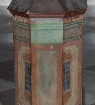 Zdjęcie nr 6: Tabernakulum w formie drewnianej skrzynki, zamkniętej trójbocznie, imitującej budynek, przykrytej wielospadowym dachem, na profilowanym cokole. Drzwiczki dwuskrzydłowe, w kształcie stojącego prostokąta, zwieńczone trójkątnym szczytem, zamocowane na zawiasach z okuciami. Dekorowane malowanymi płycinami o fantazyjnym kształcie i ornamentem.  Ścianki boczne z malowaną architekturą w kolorze jasnobrązowym, dwuosiowe, wydzielone pilastrami dźwigającymi belkowanie. Na osiach malowane okienka w dekoracyjnych opaskach. Na tylnej ściance namalowane belkowanie oraz dwie połówki okien w dekoracyjnych opaskach. Wnętrze tabernakulum polichromowane w kolorze jasnoniebieskim ze złoconymi gwiazdami. Drzwiczki po wewnętrznej stronie z malowaną dekoracją w postaci cokołów z wazonami i kwiatami, na jasnoniebieskim tle, w górnej partii ornament. 
