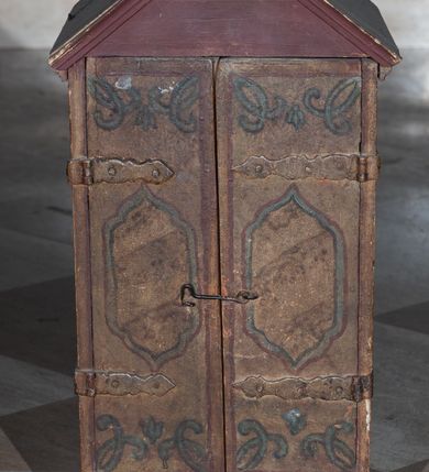 Zdjęcie nr 2: Tabernakulum w formie drewnianej skrzynki, zamkniętej trójbocznie, imitującej budynek, przykrytej wielospadowym dachem, na profilowanym cokole. Drzwiczki dwuskrzydłowe, w kształcie stojącego prostokąta, zwieńczone trójkątnym szczytem, zamocowane na zawiasach z okuciami. Dekorowane malowanymi płycinami o fantazyjnym kształcie i ornamentem.  Ścianki boczne z malowaną architekturą w kolorze jasnobrązowym, dwuosiowe, wydzielone pilastrami dźwigającymi belkowanie. Na osiach malowane okienka w dekoracyjnych opaskach. Na tylnej ściance namalowane belkowanie oraz dwie połówki okien w dekoracyjnych opaskach. Wnętrze tabernakulum polichromowane w kolorze jasnoniebieskim ze złoconymi gwiazdami. Drzwiczki po wewnętrznej stronie z malowaną dekoracją w postaci cokołów z wazonami i kwiatami, na jasnoniebieskim tle, w górnej partii ornament. 
