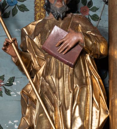 Zdjęcie nr 2: Rzeźba ścięta i drążona z tyłu, ustawiona na niskiej podstawie. Święty zwrócony frontalnie, w kontrapoście, z przechyloną łukowato sylwetką i głową skierowaną delikatnie w lewo. Lewą ręką przyciska do piersi księgę, w prawej, ugiętej trzyma szuflę pasterską. Twarz ma pociągłą, szczupłą, z wysokim czołem, o małych oczach skierowanych w górę, z głęboko rzeźbioną górną powieką, o dużym nosie i pełnych ustach o szerokiej górnej wardze. Twarz okolona kręconą, rozdwajającą się brodą oraz włosami o grubych falach opadającymi na ramiona. Ubrany jest w długą tunikę o wąskich rękawach, przepasaną w talii, przylegającą do ciała. Przez prawe ramię ma przerzucony silnie drapowany płaszcz, opadający na plecy i na prawy bok postaci. Polichromia ciała naturalistyczna, szaty i atrybut złocone.