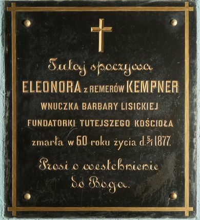 Zdjęcie nr 1: Płyta w formie stojącego prostokąta, przymocowana do ściany czterema śrubami, znajdującymi się w narożach. Wzdłuż krawędzi złocona ramka. W polu złocona inskrypcja: „Tutaj spoczywa / ELEONORA z REMERÓW KEMPNER / WNUCZKA BARBARY LISICKIEJ / FUNDATORKI TUTEJSZEGO KOŚCIOŁA / zmarła w 60 roku życia d(nia) 5/I 1877. / Prosi o westchnienie do Boga.” Ponad inskrypcją złocony krzyż. 