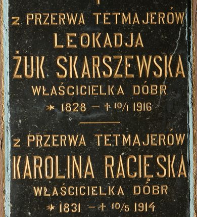 Zdjęcie nr 1: Płyta w formie wydłużonego stojącego prostokąta. Przymocowana do ściany dwiema ślubami o dekoracyjnych łbach w formie rozet, zamocowanymi przy krótszych bokach. W polu złocona inskrypcja: „Z PRZERWA TETMAJERÓW / LEOKADJA / ŻUK SKARSZEWSKA / WŁAŚCICIELKA DÓBR / *1828 +10/I 1916 / Z PRZERWA TETMAJERÓW / KAROLINA RACIĘSKA / WŁAŚCICIELKA DÓBR *1831 +10/5 1914 / PROSZĄ O ZDROWAŚ MARYA.”