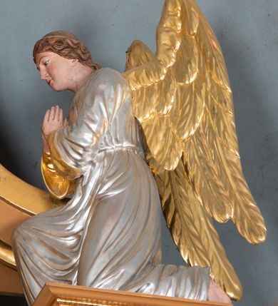 Zdjęcie nr 9: Nastawa ołtarzowa architektoniczna, jednoosiowa, jednokondygnacyjna z bramkami i zwieńczeniem, ustawiona na wysokim, dwustrefowym cokole. Ołtarz prostopadłościenny, murowany, umieszczony w drewnianej obudowie. Antependium ujęte ramą dekorowaną plecionką, podzielone na trzy pola: w środkowym płaskorzeźbione przedstawienie Ostatniej Wieczerzy według Leonarda da Vinci, a po bokach ornament roślinny o wertykalnym układzie.

Tabernakulum architektoniczne, jednokondygnacyjne, trójosiowe, ustawione na zdwojonym na cokole z dwoma zwieńczeniami na osiach skrajnych. Osie wydzielone są parami kolumn o kapitelach kompozytowych, oś środkowa wysunięta do przodu. Podpory dźwigają pełne belkowanie wyłamane na ich linii, przerwane nad polem środkowym, gdzie kolumny dźwigają przerwany półkolisty przyczółek połączony z łukiem gzymsu, nad nim ustawiona jest rzeźba Baranka leżącego na księdze z siedmioma pieczęciami. W polu środkowym dwuskrzydłowe drzwiczki do metalowego tabernakulum ujęte ramą w formie stojącego prostokąta, zamkniętego łukiem nadwieszonym z długim uskokiem. Na drzwiczkach znajdują się dwa aplikowane klęczące anioły, powyżej Chrismo w medalionie, otoczonym glorią. W osiach bocznych są nisze zamknięte konchami z figurkami aniołów, zamknięte zwieńczeniami w formie stojących prostokątów z falistym gzymsem i gałązkami lilii na szczycie; w polu srebrzone, owalne medaliony. Po bokach kondygnacji na wolutowych uszach oraz po bokach zwieńczeń znajdują się wazony ze słonecznikami. Cokół zdobiony jest ornamentem akantowym.

Kondygnacja ujęta jest dwiema parami kolumn o kapitelach kompozytowych oraz stojącą między nimi parą filarów. Podpory dźwigają pełne belkowanie o silnie wysuniętym gzymsie, wyłamane na osiach bocznych, z podwieszonymi szyszkami na tle filarów; przerwane nad polem środkowym. W centrum pole w formie stojącego prostokąta ujęte ramą dekorowaną ornamentem roślinnym z płaskorzeźbionym przedstawieniem Matki Boskiej z Dzieciątkiem. Na zasuwie obrazy: „Najświętsze Serce Pana Jezusa”, „Zwiastowanie” oraz „Św. Mikołaj”. Nad bramkami oraz pomiędzy kolumnami ustawione są rzeźby. Od lewej kolejno: św. Andrzej, św. Wojciech, św. Stanisław i na końcu po prawej św. Tomasz. Nad polem głównym znajduje się przeszklony prześwit w formie półkola z rzeźbioną gołębicą Ducha Świętego na tle glorii. Powyżej pole zamknięte półkoliście fragmentem gzymsu z rzeźbionym popiersiem błogosławiącego Boga Ojca pośród obłoków. Zwieńczenie w formie zbliżonej do stojącego prostokąta o wklęsłych bokach z gzymsem i z podwieszonym lambrekinem oraz kotarami spływającymi na boki. W polu przeszklony prześwit w formie kwadratu zamkniętego łukiem nadwieszonym z rzeźbionym monogramem Marii na tle glorii. Po bokach zwieńczenia ustawione są dwie duże figury klęczących aniołów.

Bramki po bokach ołtarza ustawione są na wysokości cokołu nastawy; przejścia ujęte są parą kanelowanych pilastrów, zamknięte łukiem utworzonym z dwóch przeciwstawnych wolut wspierających wieńczące cokoły. Przejścia w formie wydłużonego stojącego prostokąta zamkniętego łukiem półkolistym nadwieszonym.

Całość ołtarza oprócz tabernakulum dekorowana jest ornamentem małżowinowo-chrząstkowym. Uszy flankujące kondygnację utworzone są również z ornamentu małżowinowo-chrząstkowego. Na zamknięciu zwieńczenia znajdują się dwie uskrzydlone główki anielskie skierowane na wprost z podwieszonymi u szyi chustami. Struktura ołtarza polichromowana jest w kolorze brązowym ze złoconymi kolumnami, ornamentyką i profilami, detale srebrzone.