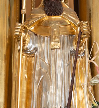 Zdjęcie nr 18: Nastawa ołtarzowa architektoniczna, jednoosiowa, jednokondygnacyjna z bramkami i zwieńczeniem, ustawiona na wysokim, dwustrefowym cokole. Ołtarz prostopadłościenny, murowany, umieszczony w drewnianej obudowie. Antependium ujęte ramą dekorowaną plecionką, podzielone na trzy pola: w środkowym płaskorzeźbione przedstawienie Ostatniej Wieczerzy według Leonarda da Vinci, a po bokach ornament roślinny o wertykalnym układzie.

Tabernakulum architektoniczne, jednokondygnacyjne, trójosiowe, ustawione na zdwojonym na cokole z dwoma zwieńczeniami na osiach skrajnych. Osie wydzielone są parami kolumn o kapitelach kompozytowych, oś środkowa wysunięta do przodu. Podpory dźwigają pełne belkowanie wyłamane na ich linii, przerwane nad polem środkowym, gdzie kolumny dźwigają przerwany półkolisty przyczółek połączony z łukiem gzymsu, nad nim ustawiona jest rzeźba Baranka leżącego na księdze z siedmioma pieczęciami. W polu środkowym dwuskrzydłowe drzwiczki do metalowego tabernakulum ujęte ramą w formie stojącego prostokąta, zamkniętego łukiem nadwieszonym z długim uskokiem. Na drzwiczkach znajdują się dwa aplikowane klęczące anioły, powyżej Chrismo w medalionie, otoczonym glorią. W osiach bocznych są nisze zamknięte konchami z figurkami aniołów, zamknięte zwieńczeniami w formie stojących prostokątów z falistym gzymsem i gałązkami lilii na szczycie; w polu srebrzone, owalne medaliony. Po bokach kondygnacji na wolutowych uszach oraz po bokach zwieńczeń znajdują się wazony ze słonecznikami. Cokół zdobiony jest ornamentem akantowym.

Kondygnacja ujęta jest dwiema parami kolumn o kapitelach kompozytowych oraz stojącą między nimi parą filarów. Podpory dźwigają pełne belkowanie o silnie wysuniętym gzymsie, wyłamane na osiach bocznych, z podwieszonymi szyszkami na tle filarów; przerwane nad polem środkowym. W centrum pole w formie stojącego prostokąta ujęte ramą dekorowaną ornamentem roślinnym z płaskorzeźbionym przedstawieniem Matki Boskiej z Dzieciątkiem. Na zasuwie obrazy: „Najświętsze Serce Pana Jezusa”, „Zwiastowanie” oraz „Św. Mikołaj”. Nad bramkami oraz pomiędzy kolumnami ustawione są rzeźby. Od lewej kolejno: św. Andrzej, św. Wojciech, św. Stanisław i na końcu po prawej św. Tomasz. Nad polem głównym znajduje się przeszklony prześwit w formie półkola z rzeźbioną gołębicą Ducha Świętego na tle glorii. Powyżej pole zamknięte półkoliście fragmentem gzymsu z rzeźbionym popiersiem błogosławiącego Boga Ojca pośród obłoków. Zwieńczenie w formie zbliżonej do stojącego prostokąta o wklęsłych bokach z gzymsem i z podwieszonym lambrekinem oraz kotarami spływającymi na boki. W polu przeszklony prześwit w formie kwadratu zamkniętego łukiem nadwieszonym z rzeźbionym monogramem Marii na tle glorii. Po bokach zwieńczenia ustawione są dwie duże figury klęczących aniołów.

Bramki po bokach ołtarza ustawione są na wysokości cokołu nastawy; przejścia ujęte są parą kanelowanych pilastrów, zamknięte łukiem utworzonym z dwóch przeciwstawnych wolut wspierających wieńczące cokoły. Przejścia w formie wydłużonego stojącego prostokąta zamkniętego łukiem półkolistym nadwieszonym.

Całość ołtarza oprócz tabernakulum dekorowana jest ornamentem małżowinowo-chrząstkowym. Uszy flankujące kondygnację utworzone są również z ornamentu małżowinowo-chrząstkowego. Na zamknięciu zwieńczenia znajdują się dwie uskrzydlone główki anielskie skierowane na wprost z podwieszonymi u szyi chustami. Struktura ołtarza polichromowana jest w kolorze brązowym ze złoconymi kolumnami, ornamentyką i profilami, detale srebrzone.