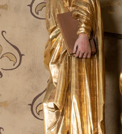 Zdjęcie nr 21: Nastawa ołtarzowa architektoniczna, jednoosiowa, jednokondygnacyjna z bramkami i zwieńczeniem, ustawiona na wysokim, dwustrefowym cokole. Ołtarz prostopadłościenny, murowany, umieszczony w drewnianej obudowie. Antependium ujęte ramą dekorowaną plecionką, podzielone na trzy pola: w środkowym płaskorzeźbione przedstawienie Ostatniej Wieczerzy według Leonarda da Vinci, a po bokach ornament roślinny o wertykalnym układzie.

Tabernakulum architektoniczne, jednokondygnacyjne, trójosiowe, ustawione na zdwojonym na cokole z dwoma zwieńczeniami na osiach skrajnych. Osie wydzielone są parami kolumn o kapitelach kompozytowych, oś środkowa wysunięta do przodu. Podpory dźwigają pełne belkowanie wyłamane na ich linii, przerwane nad polem środkowym, gdzie kolumny dźwigają przerwany półkolisty przyczółek połączony z łukiem gzymsu, nad nim ustawiona jest rzeźba Baranka leżącego na księdze z siedmioma pieczęciami. W polu środkowym dwuskrzydłowe drzwiczki do metalowego tabernakulum ujęte ramą w formie stojącego prostokąta, zamkniętego łukiem nadwieszonym z długim uskokiem. Na drzwiczkach znajdują się dwa aplikowane klęczące anioły, powyżej Chrismo w medalionie, otoczonym glorią. W osiach bocznych są nisze zamknięte konchami z figurkami aniołów, zamknięte zwieńczeniami w formie stojących prostokątów z falistym gzymsem i gałązkami lilii na szczycie; w polu srebrzone, owalne medaliony. Po bokach kondygnacji na wolutowych uszach oraz po bokach zwieńczeń znajdują się wazony ze słonecznikami. Cokół zdobiony jest ornamentem akantowym.

Kondygnacja ujęta jest dwiema parami kolumn o kapitelach kompozytowych oraz stojącą między nimi parą filarów. Podpory dźwigają pełne belkowanie o silnie wysuniętym gzymsie, wyłamane na osiach bocznych, z podwieszonymi szyszkami na tle filarów; przerwane nad polem środkowym. W centrum pole w formie stojącego prostokąta ujęte ramą dekorowaną ornamentem roślinnym z płaskorzeźbionym przedstawieniem Matki Boskiej z Dzieciątkiem. Na zasuwie obrazy: „Najświętsze Serce Pana Jezusa”, „Zwiastowanie” oraz „Św. Mikołaj”. Nad bramkami oraz pomiędzy kolumnami ustawione są rzeźby. Od lewej kolejno: św. Andrzej, św. Wojciech, św. Stanisław i na końcu po prawej św. Tomasz. Nad polem głównym znajduje się przeszklony prześwit w formie półkola z rzeźbioną gołębicą Ducha Świętego na tle glorii. Powyżej pole zamknięte półkoliście fragmentem gzymsu z rzeźbionym popiersiem błogosławiącego Boga Ojca pośród obłoków. Zwieńczenie w formie zbliżonej do stojącego prostokąta o wklęsłych bokach z gzymsem i z podwieszonym lambrekinem oraz kotarami spływającymi na boki. W polu przeszklony prześwit w formie kwadratu zamkniętego łukiem nadwieszonym z rzeźbionym monogramem Marii na tle glorii. Po bokach zwieńczenia ustawione są dwie duże figury klęczących aniołów.

Bramki po bokach ołtarza ustawione są na wysokości cokołu nastawy; przejścia ujęte są parą kanelowanych pilastrów, zamknięte łukiem utworzonym z dwóch przeciwstawnych wolut wspierających wieńczące cokoły. Przejścia w formie wydłużonego stojącego prostokąta zamkniętego łukiem półkolistym nadwieszonym.

Całość ołtarza oprócz tabernakulum dekorowana jest ornamentem małżowinowo-chrząstkowym. Uszy flankujące kondygnację utworzone są również z ornamentu małżowinowo-chrząstkowego. Na zamknięciu zwieńczenia znajdują się dwie uskrzydlone główki anielskie skierowane na wprost z podwieszonymi u szyi chustami. Struktura ołtarza polichromowana jest w kolorze brązowym ze złoconymi kolumnami, ornamentyką i profilami, detale srebrzone.