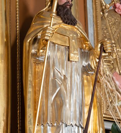 Zdjęcie nr 17: Nastawa ołtarzowa architektoniczna, jednoosiowa, jednokondygnacyjna z bramkami i zwieńczeniem, ustawiona na wysokim, dwustrefowym cokole. Ołtarz prostopadłościenny, murowany, umieszczony w drewnianej obudowie. Antependium ujęte ramą dekorowaną plecionką, podzielone na trzy pola: w środkowym płaskorzeźbione przedstawienie Ostatniej Wieczerzy według Leonarda da Vinci, a po bokach ornament roślinny o wertykalnym układzie.

Tabernakulum architektoniczne, jednokondygnacyjne, trójosiowe, ustawione na zdwojonym na cokole z dwoma zwieńczeniami na osiach skrajnych. Osie wydzielone są parami kolumn o kapitelach kompozytowych, oś środkowa wysunięta do przodu. Podpory dźwigają pełne belkowanie wyłamane na ich linii, przerwane nad polem środkowym, gdzie kolumny dźwigają przerwany półkolisty przyczółek połączony z łukiem gzymsu, nad nim ustawiona jest rzeźba Baranka leżącego na księdze z siedmioma pieczęciami. W polu środkowym dwuskrzydłowe drzwiczki do metalowego tabernakulum ujęte ramą w formie stojącego prostokąta, zamkniętego łukiem nadwieszonym z długim uskokiem. Na drzwiczkach znajdują się dwa aplikowane klęczące anioły, powyżej Chrismo w medalionie, otoczonym glorią. W osiach bocznych są nisze zamknięte konchami z figurkami aniołów, zamknięte zwieńczeniami w formie stojących prostokątów z falistym gzymsem i gałązkami lilii na szczycie; w polu srebrzone, owalne medaliony. Po bokach kondygnacji na wolutowych uszach oraz po bokach zwieńczeń znajdują się wazony ze słonecznikami. Cokół zdobiony jest ornamentem akantowym.

Kondygnacja ujęta jest dwiema parami kolumn o kapitelach kompozytowych oraz stojącą między nimi parą filarów. Podpory dźwigają pełne belkowanie o silnie wysuniętym gzymsie, wyłamane na osiach bocznych, z podwieszonymi szyszkami na tle filarów; przerwane nad polem środkowym. W centrum pole w formie stojącego prostokąta ujęte ramą dekorowaną ornamentem roślinnym z płaskorzeźbionym przedstawieniem Matki Boskiej z Dzieciątkiem. Na zasuwie obrazy: „Najświętsze Serce Pana Jezusa”, „Zwiastowanie” oraz „Św. Mikołaj”. Nad bramkami oraz pomiędzy kolumnami ustawione są rzeźby. Od lewej kolejno: św. Andrzej, św. Wojciech, św. Stanisław i na końcu po prawej św. Tomasz. Nad polem głównym znajduje się przeszklony prześwit w formie półkola z rzeźbioną gołębicą Ducha Świętego na tle glorii. Powyżej pole zamknięte półkoliście fragmentem gzymsu z rzeźbionym popiersiem błogosławiącego Boga Ojca pośród obłoków. Zwieńczenie w formie zbliżonej do stojącego prostokąta o wklęsłych bokach z gzymsem i z podwieszonym lambrekinem oraz kotarami spływającymi na boki. W polu przeszklony prześwit w formie kwadratu zamkniętego łukiem nadwieszonym z rzeźbionym monogramem Marii na tle glorii. Po bokach zwieńczenia ustawione są dwie duże figury klęczących aniołów.

Bramki po bokach ołtarza ustawione są na wysokości cokołu nastawy; przejścia ujęte są parą kanelowanych pilastrów, zamknięte łukiem utworzonym z dwóch przeciwstawnych wolut wspierających wieńczące cokoły. Przejścia w formie wydłużonego stojącego prostokąta zamkniętego łukiem półkolistym nadwieszonym.

Całość ołtarza oprócz tabernakulum dekorowana jest ornamentem małżowinowo-chrząstkowym. Uszy flankujące kondygnację utworzone są również z ornamentu małżowinowo-chrząstkowego. Na zamknięciu zwieńczenia znajdują się dwie uskrzydlone główki anielskie skierowane na wprost z podwieszonymi u szyi chustami. Struktura ołtarza polichromowana jest w kolorze brązowym ze złoconymi kolumnami, ornamentyką i profilami, detale srebrzone.