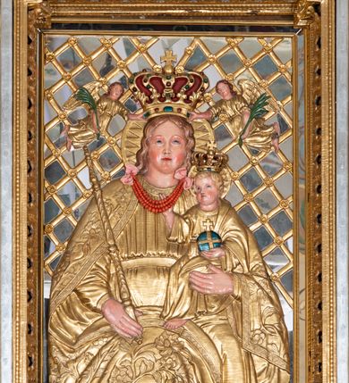 Zdjęcie nr 34: Nastawa ołtarzowa architektoniczna, jednoosiowa, jednokondygnacyjna z bramkami i zwieńczeniem, ustawiona na wysokim, dwustrefowym cokole. Ołtarz prostopadłościenny, murowany, umieszczony w drewnianej obudowie. Antependium ujęte ramą dekorowaną plecionką, podzielone na trzy pola: w środkowym płaskorzeźbione przedstawienie Ostatniej Wieczerzy według Leonarda da Vinci, a po bokach ornament roślinny o wertykalnym układzie.

Tabernakulum architektoniczne, jednokondygnacyjne, trójosiowe, ustawione na zdwojonym na cokole z dwoma zwieńczeniami na osiach skrajnych. Osie wydzielone są parami kolumn o kapitelach kompozytowych, oś środkowa wysunięta do przodu. Podpory dźwigają pełne belkowanie wyłamane na ich linii, przerwane nad polem środkowym, gdzie kolumny dźwigają przerwany półkolisty przyczółek połączony z łukiem gzymsu, nad nim ustawiona jest rzeźba Baranka leżącego na księdze z siedmioma pieczęciami. W polu środkowym dwuskrzydłowe drzwiczki do metalowego tabernakulum ujęte ramą w formie stojącego prostokąta, zamkniętego łukiem nadwieszonym z długim uskokiem. Na drzwiczkach znajdują się dwa aplikowane klęczące anioły, powyżej Chrismo w medalionie, otoczonym glorią. W osiach bocznych są nisze zamknięte konchami z figurkami aniołów, zamknięte zwieńczeniami w formie stojących prostokątów z falistym gzymsem i gałązkami lilii na szczycie; w polu srebrzone, owalne medaliony. Po bokach kondygnacji na wolutowych uszach oraz po bokach zwieńczeń znajdują się wazony ze słonecznikami. Cokół zdobiony jest ornamentem akantowym.

Kondygnacja ujęta jest dwiema parami kolumn o kapitelach kompozytowych oraz stojącą między nimi parą filarów. Podpory dźwigają pełne belkowanie o silnie wysuniętym gzymsie, wyłamane na osiach bocznych, z podwieszonymi szyszkami na tle filarów; przerwane nad polem środkowym. W centrum pole w formie stojącego prostokąta ujęte ramą dekorowaną ornamentem roślinnym z płaskorzeźbionym przedstawieniem Matki Boskiej z Dzieciątkiem. Na zasuwie obrazy: „Najświętsze Serce Pana Jezusa”, „Zwiastowanie” oraz „Św. Mikołaj”. Nad bramkami oraz pomiędzy kolumnami ustawione są rzeźby. Od lewej kolejno: św. Andrzej, św. Wojciech, św. Stanisław i na końcu po prawej św. Tomasz. Nad polem głównym znajduje się przeszklony prześwit w formie półkola z rzeźbioną gołębicą Ducha Świętego na tle glorii. Powyżej pole zamknięte półkoliście fragmentem gzymsu z rzeźbionym popiersiem błogosławiącego Boga Ojca pośród obłoków. Zwieńczenie w formie zbliżonej do stojącego prostokąta o wklęsłych bokach z gzymsem i z podwieszonym lambrekinem oraz kotarami spływającymi na boki. W polu przeszklony prześwit w formie kwadratu zamkniętego łukiem nadwieszonym z rzeźbionym monogramem Marii na tle glorii. Po bokach zwieńczenia ustawione są dwie duże figury klęczących aniołów.

Bramki po bokach ołtarza ustawione są na wysokości cokołu nastawy; przejścia ujęte są parą kanelowanych pilastrów, zamknięte łukiem utworzonym z dwóch przeciwstawnych wolut wspierających wieńczące cokoły. Przejścia w formie wydłużonego stojącego prostokąta zamkniętego łukiem półkolistym nadwieszonym.

Całość ołtarza oprócz tabernakulum dekorowana jest ornamentem małżowinowo-chrząstkowym. Uszy flankujące kondygnację utworzone są również z ornamentu małżowinowo-chrząstkowego. Na zamknięciu zwieńczenia znajdują się dwie uskrzydlone główki anielskie skierowane na wprost z podwieszonymi u szyi chustami. Struktura ołtarza polichromowana jest w kolorze brązowym ze złoconymi kolumnami, ornamentyką i profilami, detale srebrzone.