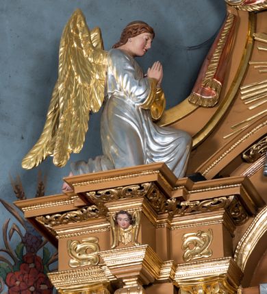 Zdjęcie nr 26: Nastawa ołtarzowa architektoniczna, jednoosiowa, jednokondygnacyjna z bramkami i zwieńczeniem, ustawiona na wysokim, dwustrefowym cokole. Ołtarz prostopadłościenny, murowany, umieszczony w drewnianej obudowie. Antependium ujęte ramą dekorowaną plecionką, podzielone na trzy pola: w środkowym płaskorzeźbione przedstawienie Ostatniej Wieczerzy według Leonarda da Vinci, a po bokach ornament roślinny o wertykalnym układzie.

Tabernakulum architektoniczne, jednokondygnacyjne, trójosiowe, ustawione na zdwojonym na cokole z dwoma zwieńczeniami na osiach skrajnych. Osie wydzielone są parami kolumn o kapitelach kompozytowych, oś środkowa wysunięta do przodu. Podpory dźwigają pełne belkowanie wyłamane na ich linii, przerwane nad polem środkowym, gdzie kolumny dźwigają przerwany półkolisty przyczółek połączony z łukiem gzymsu, nad nim ustawiona jest rzeźba Baranka leżącego na księdze z siedmioma pieczęciami. W polu środkowym dwuskrzydłowe drzwiczki do metalowego tabernakulum ujęte ramą w formie stojącego prostokąta, zamkniętego łukiem nadwieszonym z długim uskokiem. Na drzwiczkach znajdują się dwa aplikowane klęczące anioły, powyżej Chrismo w medalionie, otoczonym glorią. W osiach bocznych są nisze zamknięte konchami z figurkami aniołów, zamknięte zwieńczeniami w formie stojących prostokątów z falistym gzymsem i gałązkami lilii na szczycie; w polu srebrzone, owalne medaliony. Po bokach kondygnacji na wolutowych uszach oraz po bokach zwieńczeń znajdują się wazony ze słonecznikami. Cokół zdobiony jest ornamentem akantowym.

Kondygnacja ujęta jest dwiema parami kolumn o kapitelach kompozytowych oraz stojącą między nimi parą filarów. Podpory dźwigają pełne belkowanie o silnie wysuniętym gzymsie, wyłamane na osiach bocznych, z podwieszonymi szyszkami na tle filarów; przerwane nad polem środkowym. W centrum pole w formie stojącego prostokąta ujęte ramą dekorowaną ornamentem roślinnym z płaskorzeźbionym przedstawieniem Matki Boskiej z Dzieciątkiem. Na zasuwie obrazy: „Najświętsze Serce Pana Jezusa”, „Zwiastowanie” oraz „Św. Mikołaj”. Nad bramkami oraz pomiędzy kolumnami ustawione są rzeźby. Od lewej kolejno: św. Andrzej, św. Wojciech, św. Stanisław i na końcu po prawej św. Tomasz. Nad polem głównym znajduje się przeszklony prześwit w formie półkola z rzeźbioną gołębicą Ducha Świętego na tle glorii. Powyżej pole zamknięte półkoliście fragmentem gzymsu z rzeźbionym popiersiem błogosławiącego Boga Ojca pośród obłoków. Zwieńczenie w formie zbliżonej do stojącego prostokąta o wklęsłych bokach z gzymsem i z podwieszonym lambrekinem oraz kotarami spływającymi na boki. W polu przeszklony prześwit w formie kwadratu zamkniętego łukiem nadwieszonym z rzeźbionym monogramem Marii na tle glorii. Po bokach zwieńczenia ustawione są dwie duże figury klęczących aniołów.

Bramki po bokach ołtarza ustawione są na wysokości cokołu nastawy; przejścia ujęte są parą kanelowanych pilastrów, zamknięte łukiem utworzonym z dwóch przeciwstawnych wolut wspierających wieńczące cokoły. Przejścia w formie wydłużonego stojącego prostokąta zamkniętego łukiem półkolistym nadwieszonym.

Całość ołtarza oprócz tabernakulum dekorowana jest ornamentem małżowinowo-chrząstkowym. Uszy flankujące kondygnację utworzone są również z ornamentu małżowinowo-chrząstkowego. Na zamknięciu zwieńczenia znajdują się dwie uskrzydlone główki anielskie skierowane na wprost z podwieszonymi u szyi chustami. Struktura ołtarza polichromowana jest w kolorze brązowym ze złoconymi kolumnami, ornamentyką i profilami, detale srebrzone.