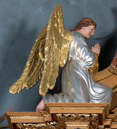 Zdjęcie nr 25: Nastawa ołtarzowa architektoniczna, jednoosiowa, jednokondygnacyjna z bramkami i zwieńczeniem, ustawiona na wysokim, dwustrefowym cokole. Ołtarz prostopadłościenny, murowany, umieszczony w drewnianej obudowie. Antependium ujęte ramą dekorowaną plecionką, podzielone na trzy pola: w środkowym płaskorzeźbione przedstawienie Ostatniej Wieczerzy według Leonarda da Vinci, a po bokach ornament roślinny o wertykalnym układzie.

Tabernakulum architektoniczne, jednokondygnacyjne, trójosiowe, ustawione na zdwojonym na cokole z dwoma zwieńczeniami na osiach skrajnych. Osie wydzielone są parami kolumn o kapitelach kompozytowych, oś środkowa wysunięta do przodu. Podpory dźwigają pełne belkowanie wyłamane na ich linii, przerwane nad polem środkowym, gdzie kolumny dźwigają przerwany półkolisty przyczółek połączony z łukiem gzymsu, nad nim ustawiona jest rzeźba Baranka leżącego na księdze z siedmioma pieczęciami. W polu środkowym dwuskrzydłowe drzwiczki do metalowego tabernakulum ujęte ramą w formie stojącego prostokąta, zamkniętego łukiem nadwieszonym z długim uskokiem. Na drzwiczkach znajdują się dwa aplikowane klęczące anioły, powyżej Chrismo w medalionie, otoczonym glorią. W osiach bocznych są nisze zamknięte konchami z figurkami aniołów, zamknięte zwieńczeniami w formie stojących prostokątów z falistym gzymsem i gałązkami lilii na szczycie; w polu srebrzone, owalne medaliony. Po bokach kondygnacji na wolutowych uszach oraz po bokach zwieńczeń znajdują się wazony ze słonecznikami. Cokół zdobiony jest ornamentem akantowym.

Kondygnacja ujęta jest dwiema parami kolumn o kapitelach kompozytowych oraz stojącą między nimi parą filarów. Podpory dźwigają pełne belkowanie o silnie wysuniętym gzymsie, wyłamane na osiach bocznych, z podwieszonymi szyszkami na tle filarów; przerwane nad polem środkowym. W centrum pole w formie stojącego prostokąta ujęte ramą dekorowaną ornamentem roślinnym z płaskorzeźbionym przedstawieniem Matki Boskiej z Dzieciątkiem. Na zasuwie obrazy: „Najświętsze Serce Pana Jezusa”, „Zwiastowanie” oraz „Św. Mikołaj”. Nad bramkami oraz pomiędzy kolumnami ustawione są rzeźby. Od lewej kolejno: św. Andrzej, św. Wojciech, św. Stanisław i na końcu po prawej św. Tomasz. Nad polem głównym znajduje się przeszklony prześwit w formie półkola z rzeźbioną gołębicą Ducha Świętego na tle glorii. Powyżej pole zamknięte półkoliście fragmentem gzymsu z rzeźbionym popiersiem błogosławiącego Boga Ojca pośród obłoków. Zwieńczenie w formie zbliżonej do stojącego prostokąta o wklęsłych bokach z gzymsem i z podwieszonym lambrekinem oraz kotarami spływającymi na boki. W polu przeszklony prześwit w formie kwadratu zamkniętego łukiem nadwieszonym z rzeźbionym monogramem Marii na tle glorii. Po bokach zwieńczenia ustawione są dwie duże figury klęczących aniołów.

Bramki po bokach ołtarza ustawione są na wysokości cokołu nastawy; przejścia ujęte są parą kanelowanych pilastrów, zamknięte łukiem utworzonym z dwóch przeciwstawnych wolut wspierających wieńczące cokoły. Przejścia w formie wydłużonego stojącego prostokąta zamkniętego łukiem półkolistym nadwieszonym.

Całość ołtarza oprócz tabernakulum dekorowana jest ornamentem małżowinowo-chrząstkowym. Uszy flankujące kondygnację utworzone są również z ornamentu małżowinowo-chrząstkowego. Na zamknięciu zwieńczenia znajdują się dwie uskrzydlone główki anielskie skierowane na wprost z podwieszonymi u szyi chustami. Struktura ołtarza polichromowana jest w kolorze brązowym ze złoconymi kolumnami, ornamentyką i profilami, detale srebrzone.