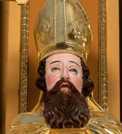 Zdjęcie nr 51: Nastawa ołtarzowa architektoniczna, jednoosiowa, jednokondygnacyjna z bramkami i zwieńczeniem, ustawiona na wysokim, dwustrefowym cokole. Ołtarz prostopadłościenny, murowany, umieszczony w drewnianej obudowie. Antependium ujęte ramą dekorowaną plecionką, podzielone na trzy pola: w środkowym płaskorzeźbione przedstawienie Ostatniej Wieczerzy według Leonarda da Vinci, a po bokach ornament roślinny o wertykalnym układzie.

Tabernakulum architektoniczne, jednokondygnacyjne, trójosiowe, ustawione na zdwojonym na cokole z dwoma zwieńczeniami na osiach skrajnych. Osie wydzielone są parami kolumn o kapitelach kompozytowych, oś środkowa wysunięta do przodu. Podpory dźwigają pełne belkowanie wyłamane na ich linii, przerwane nad polem środkowym, gdzie kolumny dźwigają przerwany półkolisty przyczółek połączony z łukiem gzymsu, nad nim ustawiona jest rzeźba Baranka leżącego na księdze z siedmioma pieczęciami. W polu środkowym dwuskrzydłowe drzwiczki do metalowego tabernakulum ujęte ramą w formie stojącego prostokąta, zamkniętego łukiem nadwieszonym z długim uskokiem. Na drzwiczkach znajdują się dwa aplikowane klęczące anioły, powyżej Chrismo w medalionie, otoczonym glorią. W osiach bocznych są nisze zamknięte konchami z figurkami aniołów, zamknięte zwieńczeniami w formie stojących prostokątów z falistym gzymsem i gałązkami lilii na szczycie; w polu srebrzone, owalne medaliony. Po bokach kondygnacji na wolutowych uszach oraz po bokach zwieńczeń znajdują się wazony ze słonecznikami. Cokół zdobiony jest ornamentem akantowym.

Kondygnacja ujęta jest dwiema parami kolumn o kapitelach kompozytowych oraz stojącą między nimi parą filarów. Podpory dźwigają pełne belkowanie o silnie wysuniętym gzymsie, wyłamane na osiach bocznych, z podwieszonymi szyszkami na tle filarów; przerwane nad polem środkowym. W centrum pole w formie stojącego prostokąta ujęte ramą dekorowaną ornamentem roślinnym z płaskorzeźbionym przedstawieniem Matki Boskiej z Dzieciątkiem. Na zasuwie obrazy: „Najświętsze Serce Pana Jezusa”, „Zwiastowanie” oraz „Św. Mikołaj”. Nad bramkami oraz pomiędzy kolumnami ustawione są rzeźby. Od lewej kolejno: św. Andrzej, św. Wojciech, św. Stanisław i na końcu po prawej św. Tomasz. Nad polem głównym znajduje się przeszklony prześwit w formie półkola z rzeźbioną gołębicą Ducha Świętego na tle glorii. Powyżej pole zamknięte półkoliście fragmentem gzymsu z rzeźbionym popiersiem błogosławiącego Boga Ojca pośród obłoków. Zwieńczenie w formie zbliżonej do stojącego prostokąta o wklęsłych bokach z gzymsem i z podwieszonym lambrekinem oraz kotarami spływającymi na boki. W polu przeszklony prześwit w formie kwadratu zamkniętego łukiem nadwieszonym z rzeźbionym monogramem Marii na tle glorii. Po bokach zwieńczenia ustawione są dwie duże figury klęczących aniołów.

Bramki po bokach ołtarza ustawione są na wysokości cokołu nastawy; przejścia ujęte są parą kanelowanych pilastrów, zamknięte łukiem utworzonym z dwóch przeciwstawnych wolut wspierających wieńczące cokoły. Przejścia w formie wydłużonego stojącego prostokąta zamkniętego łukiem półkolistym nadwieszonym.

Całość ołtarza oprócz tabernakulum dekorowana jest ornamentem małżowinowo-chrząstkowym. Uszy flankujące kondygnację utworzone są również z ornamentu małżowinowo-chrząstkowego. Na zamknięciu zwieńczenia znajdują się dwie uskrzydlone główki anielskie skierowane na wprost z podwieszonymi u szyi chustami. Struktura ołtarza polichromowana jest w kolorze brązowym ze złoconymi kolumnami, ornamentyką i profilami, detale srebrzone.