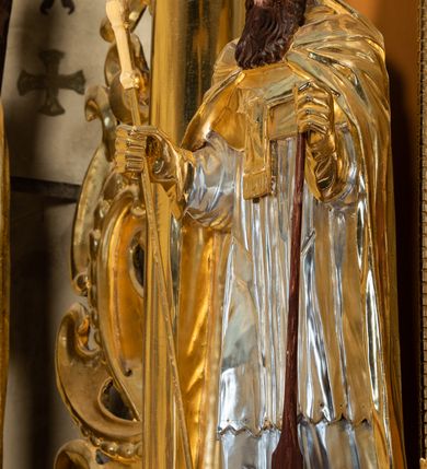 Zdjęcie nr 50: Nastawa ołtarzowa architektoniczna, jednoosiowa, jednokondygnacyjna z bramkami i zwieńczeniem, ustawiona na wysokim, dwustrefowym cokole. Ołtarz prostopadłościenny, murowany, umieszczony w drewnianej obudowie. Antependium ujęte ramą dekorowaną plecionką, podzielone na trzy pola: w środkowym płaskorzeźbione przedstawienie Ostatniej Wieczerzy według Leonarda da Vinci, a po bokach ornament roślinny o wertykalnym układzie.

Tabernakulum architektoniczne, jednokondygnacyjne, trójosiowe, ustawione na zdwojonym na cokole z dwoma zwieńczeniami na osiach skrajnych. Osie wydzielone są parami kolumn o kapitelach kompozytowych, oś środkowa wysunięta do przodu. Podpory dźwigają pełne belkowanie wyłamane na ich linii, przerwane nad polem środkowym, gdzie kolumny dźwigają przerwany półkolisty przyczółek połączony z łukiem gzymsu, nad nim ustawiona jest rzeźba Baranka leżącego na księdze z siedmioma pieczęciami. W polu środkowym dwuskrzydłowe drzwiczki do metalowego tabernakulum ujęte ramą w formie stojącego prostokąta, zamkniętego łukiem nadwieszonym z długim uskokiem. Na drzwiczkach znajdują się dwa aplikowane klęczące anioły, powyżej Chrismo w medalionie, otoczonym glorią. W osiach bocznych są nisze zamknięte konchami z figurkami aniołów, zamknięte zwieńczeniami w formie stojących prostokątów z falistym gzymsem i gałązkami lilii na szczycie; w polu srebrzone, owalne medaliony. Po bokach kondygnacji na wolutowych uszach oraz po bokach zwieńczeń znajdują się wazony ze słonecznikami. Cokół zdobiony jest ornamentem akantowym.

Kondygnacja ujęta jest dwiema parami kolumn o kapitelach kompozytowych oraz stojącą między nimi parą filarów. Podpory dźwigają pełne belkowanie o silnie wysuniętym gzymsie, wyłamane na osiach bocznych, z podwieszonymi szyszkami na tle filarów; przerwane nad polem środkowym. W centrum pole w formie stojącego prostokąta ujęte ramą dekorowaną ornamentem roślinnym z płaskorzeźbionym przedstawieniem Matki Boskiej z Dzieciątkiem. Na zasuwie obrazy: „Najświętsze Serce Pana Jezusa”, „Zwiastowanie” oraz „Św. Mikołaj”. Nad bramkami oraz pomiędzy kolumnami ustawione są rzeźby. Od lewej kolejno: św. Andrzej, św. Wojciech, św. Stanisław i na końcu po prawej św. Tomasz. Nad polem głównym znajduje się przeszklony prześwit w formie półkola z rzeźbioną gołębicą Ducha Świętego na tle glorii. Powyżej pole zamknięte półkoliście fragmentem gzymsu z rzeźbionym popiersiem błogosławiącego Boga Ojca pośród obłoków. Zwieńczenie w formie zbliżonej do stojącego prostokąta o wklęsłych bokach z gzymsem i z podwieszonym lambrekinem oraz kotarami spływającymi na boki. W polu przeszklony prześwit w formie kwadratu zamkniętego łukiem nadwieszonym z rzeźbionym monogramem Marii na tle glorii. Po bokach zwieńczenia ustawione są dwie duże figury klęczących aniołów.

Bramki po bokach ołtarza ustawione są na wysokości cokołu nastawy; przejścia ujęte są parą kanelowanych pilastrów, zamknięte łukiem utworzonym z dwóch przeciwstawnych wolut wspierających wieńczące cokoły. Przejścia w formie wydłużonego stojącego prostokąta zamkniętego łukiem półkolistym nadwieszonym.

Całość ołtarza oprócz tabernakulum dekorowana jest ornamentem małżowinowo-chrząstkowym. Uszy flankujące kondygnację utworzone są również z ornamentu małżowinowo-chrząstkowego. Na zamknięciu zwieńczenia znajdują się dwie uskrzydlone główki anielskie skierowane na wprost z podwieszonymi u szyi chustami. Struktura ołtarza polichromowana jest w kolorze brązowym ze złoconymi kolumnami, ornamentyką i profilami, detale srebrzone.