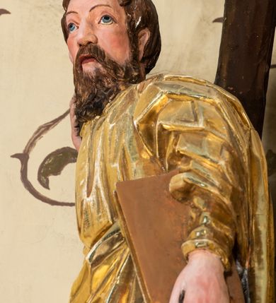 Zdjęcie nr 52: Nastawa ołtarzowa architektoniczna, jednoosiowa, jednokondygnacyjna z bramkami i zwieńczeniem, ustawiona na wysokim, dwustrefowym cokole. Ołtarz prostopadłościenny, murowany, umieszczony w drewnianej obudowie. Antependium ujęte ramą dekorowaną plecionką, podzielone na trzy pola: w środkowym płaskorzeźbione przedstawienie Ostatniej Wieczerzy według Leonarda da Vinci, a po bokach ornament roślinny o wertykalnym układzie.

Tabernakulum architektoniczne, jednokondygnacyjne, trójosiowe, ustawione na zdwojonym na cokole z dwoma zwieńczeniami na osiach skrajnych. Osie wydzielone są parami kolumn o kapitelach kompozytowych, oś środkowa wysunięta do przodu. Podpory dźwigają pełne belkowanie wyłamane na ich linii, przerwane nad polem środkowym, gdzie kolumny dźwigają przerwany półkolisty przyczółek połączony z łukiem gzymsu, nad nim ustawiona jest rzeźba Baranka leżącego na księdze z siedmioma pieczęciami. W polu środkowym dwuskrzydłowe drzwiczki do metalowego tabernakulum ujęte ramą w formie stojącego prostokąta, zamkniętego łukiem nadwieszonym z długim uskokiem. Na drzwiczkach znajdują się dwa aplikowane klęczące anioły, powyżej Chrismo w medalionie, otoczonym glorią. W osiach bocznych są nisze zamknięte konchami z figurkami aniołów, zamknięte zwieńczeniami w formie stojących prostokątów z falistym gzymsem i gałązkami lilii na szczycie; w polu srebrzone, owalne medaliony. Po bokach kondygnacji na wolutowych uszach oraz po bokach zwieńczeń znajdują się wazony ze słonecznikami. Cokół zdobiony jest ornamentem akantowym.

Kondygnacja ujęta jest dwiema parami kolumn o kapitelach kompozytowych oraz stojącą między nimi parą filarów. Podpory dźwigają pełne belkowanie o silnie wysuniętym gzymsie, wyłamane na osiach bocznych, z podwieszonymi szyszkami na tle filarów; przerwane nad polem środkowym. W centrum pole w formie stojącego prostokąta ujęte ramą dekorowaną ornamentem roślinnym z płaskorzeźbionym przedstawieniem Matki Boskiej z Dzieciątkiem. Na zasuwie obrazy: „Najświętsze Serce Pana Jezusa”, „Zwiastowanie” oraz „Św. Mikołaj”. Nad bramkami oraz pomiędzy kolumnami ustawione są rzeźby. Od lewej kolejno: św. Andrzej, św. Wojciech, św. Stanisław i na końcu po prawej św. Tomasz. Nad polem głównym znajduje się przeszklony prześwit w formie półkola z rzeźbioną gołębicą Ducha Świętego na tle glorii. Powyżej pole zamknięte półkoliście fragmentem gzymsu z rzeźbionym popiersiem błogosławiącego Boga Ojca pośród obłoków. Zwieńczenie w formie zbliżonej do stojącego prostokąta o wklęsłych bokach z gzymsem i z podwieszonym lambrekinem oraz kotarami spływającymi na boki. W polu przeszklony prześwit w formie kwadratu zamkniętego łukiem nadwieszonym z rzeźbionym monogramem Marii na tle glorii. Po bokach zwieńczenia ustawione są dwie duże figury klęczących aniołów.

Bramki po bokach ołtarza ustawione są na wysokości cokołu nastawy; przejścia ujęte są parą kanelowanych pilastrów, zamknięte łukiem utworzonym z dwóch przeciwstawnych wolut wspierających wieńczące cokoły. Przejścia w formie wydłużonego stojącego prostokąta zamkniętego łukiem półkolistym nadwieszonym.

Całość ołtarza oprócz tabernakulum dekorowana jest ornamentem małżowinowo-chrząstkowym. Uszy flankujące kondygnację utworzone są również z ornamentu małżowinowo-chrząstkowego. Na zamknięciu zwieńczenia znajdują się dwie uskrzydlone główki anielskie skierowane na wprost z podwieszonymi u szyi chustami. Struktura ołtarza polichromowana jest w kolorze brązowym ze złoconymi kolumnami, ornamentyką i profilami, detale srebrzone.