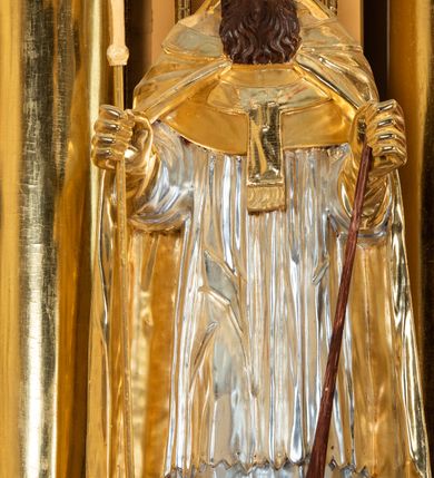 Zdjęcie nr 55: Nastawa ołtarzowa architektoniczna, jednoosiowa, jednokondygnacyjna z bramkami i zwieńczeniem, ustawiona na wysokim, dwustrefowym cokole. Ołtarz prostopadłościenny, murowany, umieszczony w drewnianej obudowie. Antependium ujęte ramą dekorowaną plecionką, podzielone na trzy pola: w środkowym płaskorzeźbione przedstawienie Ostatniej Wieczerzy według Leonarda da Vinci, a po bokach ornament roślinny o wertykalnym układzie.

Tabernakulum architektoniczne, jednokondygnacyjne, trójosiowe, ustawione na zdwojonym na cokole z dwoma zwieńczeniami na osiach skrajnych. Osie wydzielone są parami kolumn o kapitelach kompozytowych, oś środkowa wysunięta do przodu. Podpory dźwigają pełne belkowanie wyłamane na ich linii, przerwane nad polem środkowym, gdzie kolumny dźwigają przerwany półkolisty przyczółek połączony z łukiem gzymsu, nad nim ustawiona jest rzeźba Baranka leżącego na księdze z siedmioma pieczęciami. W polu środkowym dwuskrzydłowe drzwiczki do metalowego tabernakulum ujęte ramą w formie stojącego prostokąta, zamkniętego łukiem nadwieszonym z długim uskokiem. Na drzwiczkach znajdują się dwa aplikowane klęczące anioły, powyżej Chrismo w medalionie, otoczonym glorią. W osiach bocznych są nisze zamknięte konchami z figurkami aniołów, zamknięte zwieńczeniami w formie stojących prostokątów z falistym gzymsem i gałązkami lilii na szczycie; w polu srebrzone, owalne medaliony. Po bokach kondygnacji na wolutowych uszach oraz po bokach zwieńczeń znajdują się wazony ze słonecznikami. Cokół zdobiony jest ornamentem akantowym.

Kondygnacja ujęta jest dwiema parami kolumn o kapitelach kompozytowych oraz stojącą między nimi parą filarów. Podpory dźwigają pełne belkowanie o silnie wysuniętym gzymsie, wyłamane na osiach bocznych, z podwieszonymi szyszkami na tle filarów; przerwane nad polem środkowym. W centrum pole w formie stojącego prostokąta ujęte ramą dekorowaną ornamentem roślinnym z płaskorzeźbionym przedstawieniem Matki Boskiej z Dzieciątkiem. Na zasuwie obrazy: „Najświętsze Serce Pana Jezusa”, „Zwiastowanie” oraz „Św. Mikołaj”. Nad bramkami oraz pomiędzy kolumnami ustawione są rzeźby. Od lewej kolejno: św. Andrzej, św. Wojciech, św. Stanisław i na końcu po prawej św. Tomasz. Nad polem głównym znajduje się przeszklony prześwit w formie półkola z rzeźbioną gołębicą Ducha Świętego na tle glorii. Powyżej pole zamknięte półkoliście fragmentem gzymsu z rzeźbionym popiersiem błogosławiącego Boga Ojca pośród obłoków. Zwieńczenie w formie zbliżonej do stojącego prostokąta o wklęsłych bokach z gzymsem i z podwieszonym lambrekinem oraz kotarami spływającymi na boki. W polu przeszklony prześwit w formie kwadratu zamkniętego łukiem nadwieszonym z rzeźbionym monogramem Marii na tle glorii. Po bokach zwieńczenia ustawione są dwie duże figury klęczących aniołów.

Bramki po bokach ołtarza ustawione są na wysokości cokołu nastawy; przejścia ujęte są parą kanelowanych pilastrów, zamknięte łukiem utworzonym z dwóch przeciwstawnych wolut wspierających wieńczące cokoły. Przejścia w formie wydłużonego stojącego prostokąta zamkniętego łukiem półkolistym nadwieszonym.

Całość ołtarza oprócz tabernakulum dekorowana jest ornamentem małżowinowo-chrząstkowym. Uszy flankujące kondygnację utworzone są również z ornamentu małżowinowo-chrząstkowego. Na zamknięciu zwieńczenia znajdują się dwie uskrzydlone główki anielskie skierowane na wprost z podwieszonymi u szyi chustami. Struktura ołtarza polichromowana jest w kolorze brązowym ze złoconymi kolumnami, ornamentyką i profilami, detale srebrzone.