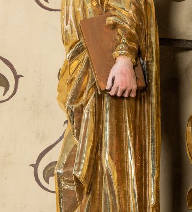 Zdjęcie nr 53: Nastawa ołtarzowa architektoniczna, jednoosiowa, jednokondygnacyjna z bramkami i zwieńczeniem, ustawiona na wysokim, dwustrefowym cokole. Ołtarz prostopadłościenny, murowany, umieszczony w drewnianej obudowie. Antependium ujęte ramą dekorowaną plecionką, podzielone na trzy pola: w środkowym płaskorzeźbione przedstawienie Ostatniej Wieczerzy według Leonarda da Vinci, a po bokach ornament roślinny o wertykalnym układzie.

Tabernakulum architektoniczne, jednokondygnacyjne, trójosiowe, ustawione na zdwojonym na cokole z dwoma zwieńczeniami na osiach skrajnych. Osie wydzielone są parami kolumn o kapitelach kompozytowych, oś środkowa wysunięta do przodu. Podpory dźwigają pełne belkowanie wyłamane na ich linii, przerwane nad polem środkowym, gdzie kolumny dźwigają przerwany półkolisty przyczółek połączony z łukiem gzymsu, nad nim ustawiona jest rzeźba Baranka leżącego na księdze z siedmioma pieczęciami. W polu środkowym dwuskrzydłowe drzwiczki do metalowego tabernakulum ujęte ramą w formie stojącego prostokąta, zamkniętego łukiem nadwieszonym z długim uskokiem. Na drzwiczkach znajdują się dwa aplikowane klęczące anioły, powyżej Chrismo w medalionie, otoczonym glorią. W osiach bocznych są nisze zamknięte konchami z figurkami aniołów, zamknięte zwieńczeniami w formie stojących prostokątów z falistym gzymsem i gałązkami lilii na szczycie; w polu srebrzone, owalne medaliony. Po bokach kondygnacji na wolutowych uszach oraz po bokach zwieńczeń znajdują się wazony ze słonecznikami. Cokół zdobiony jest ornamentem akantowym.

Kondygnacja ujęta jest dwiema parami kolumn o kapitelach kompozytowych oraz stojącą między nimi parą filarów. Podpory dźwigają pełne belkowanie o silnie wysuniętym gzymsie, wyłamane na osiach bocznych, z podwieszonymi szyszkami na tle filarów; przerwane nad polem środkowym. W centrum pole w formie stojącego prostokąta ujęte ramą dekorowaną ornamentem roślinnym z płaskorzeźbionym przedstawieniem Matki Boskiej z Dzieciątkiem. Na zasuwie obrazy: „Najświętsze Serce Pana Jezusa”, „Zwiastowanie” oraz „Św. Mikołaj”. Nad bramkami oraz pomiędzy kolumnami ustawione są rzeźby. Od lewej kolejno: św. Andrzej, św. Wojciech, św. Stanisław i na końcu po prawej św. Tomasz. Nad polem głównym znajduje się przeszklony prześwit w formie półkola z rzeźbioną gołębicą Ducha Świętego na tle glorii. Powyżej pole zamknięte półkoliście fragmentem gzymsu z rzeźbionym popiersiem błogosławiącego Boga Ojca pośród obłoków. Zwieńczenie w formie zbliżonej do stojącego prostokąta o wklęsłych bokach z gzymsem i z podwieszonym lambrekinem oraz kotarami spływającymi na boki. W polu przeszklony prześwit w formie kwadratu zamkniętego łukiem nadwieszonym z rzeźbionym monogramem Marii na tle glorii. Po bokach zwieńczenia ustawione są dwie duże figury klęczących aniołów.

Bramki po bokach ołtarza ustawione są na wysokości cokołu nastawy; przejścia ujęte są parą kanelowanych pilastrów, zamknięte łukiem utworzonym z dwóch przeciwstawnych wolut wspierających wieńczące cokoły. Przejścia w formie wydłużonego stojącego prostokąta zamkniętego łukiem półkolistym nadwieszonym.

Całość ołtarza oprócz tabernakulum dekorowana jest ornamentem małżowinowo-chrząstkowym. Uszy flankujące kondygnację utworzone są również z ornamentu małżowinowo-chrząstkowego. Na zamknięciu zwieńczenia znajdują się dwie uskrzydlone główki anielskie skierowane na wprost z podwieszonymi u szyi chustami. Struktura ołtarza polichromowana jest w kolorze brązowym ze złoconymi kolumnami, ornamentyką i profilami, detale srebrzone.