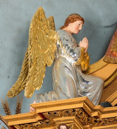 Zdjęcie nr 58: Nastawa ołtarzowa architektoniczna, jednoosiowa, jednokondygnacyjna z bramkami i zwieńczeniem, ustawiona na wysokim, dwustrefowym cokole. Ołtarz prostopadłościenny, murowany, umieszczony w drewnianej obudowie. Antependium ujęte ramą dekorowaną plecionką, podzielone na trzy pola: w środkowym płaskorzeźbione przedstawienie Ostatniej Wieczerzy według Leonarda da Vinci, a po bokach ornament roślinny o wertykalnym układzie.

Tabernakulum architektoniczne, jednokondygnacyjne, trójosiowe, ustawione na zdwojonym na cokole z dwoma zwieńczeniami na osiach skrajnych. Osie wydzielone są parami kolumn o kapitelach kompozytowych, oś środkowa wysunięta do przodu. Podpory dźwigają pełne belkowanie wyłamane na ich linii, przerwane nad polem środkowym, gdzie kolumny dźwigają przerwany półkolisty przyczółek połączony z łukiem gzymsu, nad nim ustawiona jest rzeźba Baranka leżącego na księdze z siedmioma pieczęciami. W polu środkowym dwuskrzydłowe drzwiczki do metalowego tabernakulum ujęte ramą w formie stojącego prostokąta, zamkniętego łukiem nadwieszonym z długim uskokiem. Na drzwiczkach znajdują się dwa aplikowane klęczące anioły, powyżej Chrismo w medalionie, otoczonym glorią. W osiach bocznych są nisze zamknięte konchami z figurkami aniołów, zamknięte zwieńczeniami w formie stojących prostokątów z falistym gzymsem i gałązkami lilii na szczycie; w polu srebrzone, owalne medaliony. Po bokach kondygnacji na wolutowych uszach oraz po bokach zwieńczeń znajdują się wazony ze słonecznikami. Cokół zdobiony jest ornamentem akantowym.

Kondygnacja ujęta jest dwiema parami kolumn o kapitelach kompozytowych oraz stojącą między nimi parą filarów. Podpory dźwigają pełne belkowanie o silnie wysuniętym gzymsie, wyłamane na osiach bocznych, z podwieszonymi szyszkami na tle filarów; przerwane nad polem środkowym. W centrum pole w formie stojącego prostokąta ujęte ramą dekorowaną ornamentem roślinnym z płaskorzeźbionym przedstawieniem Matki Boskiej z Dzieciątkiem. Na zasuwie obrazy: „Najświętsze Serce Pana Jezusa”, „Zwiastowanie” oraz „Św. Mikołaj”. Nad bramkami oraz pomiędzy kolumnami ustawione są rzeźby. Od lewej kolejno: św. Andrzej, św. Wojciech, św. Stanisław i na końcu po prawej św. Tomasz. Nad polem głównym znajduje się przeszklony prześwit w formie półkola z rzeźbioną gołębicą Ducha Świętego na tle glorii. Powyżej pole zamknięte półkoliście fragmentem gzymsu z rzeźbionym popiersiem błogosławiącego Boga Ojca pośród obłoków. Zwieńczenie w formie zbliżonej do stojącego prostokąta o wklęsłych bokach z gzymsem i z podwieszonym lambrekinem oraz kotarami spływającymi na boki. W polu przeszklony prześwit w formie kwadratu zamkniętego łukiem nadwieszonym z rzeźbionym monogramem Marii na tle glorii. Po bokach zwieńczenia ustawione są dwie duże figury klęczących aniołów.

Bramki po bokach ołtarza ustawione są na wysokości cokołu nastawy; przejścia ujęte są parą kanelowanych pilastrów, zamknięte łukiem utworzonym z dwóch przeciwstawnych wolut wspierających wieńczące cokoły. Przejścia w formie wydłużonego stojącego prostokąta zamkniętego łukiem półkolistym nadwieszonym.

Całość ołtarza oprócz tabernakulum dekorowana jest ornamentem małżowinowo-chrząstkowym. Uszy flankujące kondygnację utworzone są również z ornamentu małżowinowo-chrząstkowego. Na zamknięciu zwieńczenia znajdują się dwie uskrzydlone główki anielskie skierowane na wprost z podwieszonymi u szyi chustami. Struktura ołtarza polichromowana jest w kolorze brązowym ze złoconymi kolumnami, ornamentyką i profilami, detale srebrzone.