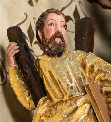 Zdjęcie nr 60: Nastawa ołtarzowa architektoniczna, jednoosiowa, jednokondygnacyjna z bramkami i zwieńczeniem, ustawiona na wysokim, dwustrefowym cokole. Ołtarz prostopadłościenny, murowany, umieszczony w drewnianej obudowie. Antependium ujęte ramą dekorowaną plecionką, podzielone na trzy pola: w środkowym płaskorzeźbione przedstawienie Ostatniej Wieczerzy według Leonarda da Vinci, a po bokach ornament roślinny o wertykalnym układzie.

Tabernakulum architektoniczne, jednokondygnacyjne, trójosiowe, ustawione na zdwojonym na cokole z dwoma zwieńczeniami na osiach skrajnych. Osie wydzielone są parami kolumn o kapitelach kompozytowych, oś środkowa wysunięta do przodu. Podpory dźwigają pełne belkowanie wyłamane na ich linii, przerwane nad polem środkowym, gdzie kolumny dźwigają przerwany półkolisty przyczółek połączony z łukiem gzymsu, nad nim ustawiona jest rzeźba Baranka leżącego na księdze z siedmioma pieczęciami. W polu środkowym dwuskrzydłowe drzwiczki do metalowego tabernakulum ujęte ramą w formie stojącego prostokąta, zamkniętego łukiem nadwieszonym z długim uskokiem. Na drzwiczkach znajdują się dwa aplikowane klęczące anioły, powyżej Chrismo w medalionie, otoczonym glorią. W osiach bocznych są nisze zamknięte konchami z figurkami aniołów, zamknięte zwieńczeniami w formie stojących prostokątów z falistym gzymsem i gałązkami lilii na szczycie; w polu srebrzone, owalne medaliony. Po bokach kondygnacji na wolutowych uszach oraz po bokach zwieńczeń znajdują się wazony ze słonecznikami. Cokół zdobiony jest ornamentem akantowym.

Kondygnacja ujęta jest dwiema parami kolumn o kapitelach kompozytowych oraz stojącą między nimi parą filarów. Podpory dźwigają pełne belkowanie o silnie wysuniętym gzymsie, wyłamane na osiach bocznych, z podwieszonymi szyszkami na tle filarów; przerwane nad polem środkowym. W centrum pole w formie stojącego prostokąta ujęte ramą dekorowaną ornamentem roślinnym z płaskorzeźbionym przedstawieniem Matki Boskiej z Dzieciątkiem. Na zasuwie obrazy: „Najświętsze Serce Pana Jezusa”, „Zwiastowanie” oraz „Św. Mikołaj”. Nad bramkami oraz pomiędzy kolumnami ustawione są rzeźby. Od lewej kolejno: św. Andrzej, św. Wojciech, św. Stanisław i na końcu po prawej św. Tomasz. Nad polem głównym znajduje się przeszklony prześwit w formie półkola z rzeźbioną gołębicą Ducha Świętego na tle glorii. Powyżej pole zamknięte półkoliście fragmentem gzymsu z rzeźbionym popiersiem błogosławiącego Boga Ojca pośród obłoków. Zwieńczenie w formie zbliżonej do stojącego prostokąta o wklęsłych bokach z gzymsem i z podwieszonym lambrekinem oraz kotarami spływającymi na boki. W polu przeszklony prześwit w formie kwadratu zamkniętego łukiem nadwieszonym z rzeźbionym monogramem Marii na tle glorii. Po bokach zwieńczenia ustawione są dwie duże figury klęczących aniołów.

Bramki po bokach ołtarza ustawione są na wysokości cokołu nastawy; przejścia ujęte są parą kanelowanych pilastrów, zamknięte łukiem utworzonym z dwóch przeciwstawnych wolut wspierających wieńczące cokoły. Przejścia w formie wydłużonego stojącego prostokąta zamkniętego łukiem półkolistym nadwieszonym.

Całość ołtarza oprócz tabernakulum dekorowana jest ornamentem małżowinowo-chrząstkowym. Uszy flankujące kondygnację utworzone są również z ornamentu małżowinowo-chrząstkowego. Na zamknięciu zwieńczenia znajdują się dwie uskrzydlone główki anielskie skierowane na wprost z podwieszonymi u szyi chustami. Struktura ołtarza polichromowana jest w kolorze brązowym ze złoconymi kolumnami, ornamentyką i profilami, detale srebrzone.