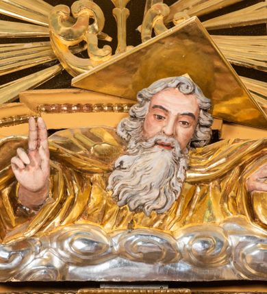 Zdjęcie nr 59: Nastawa ołtarzowa architektoniczna, jednoosiowa, jednokondygnacyjna z bramkami i zwieńczeniem, ustawiona na wysokim, dwustrefowym cokole. Ołtarz prostopadłościenny, murowany, umieszczony w drewnianej obudowie. Antependium ujęte ramą dekorowaną plecionką, podzielone na trzy pola: w środkowym płaskorzeźbione przedstawienie Ostatniej Wieczerzy według Leonarda da Vinci, a po bokach ornament roślinny o wertykalnym układzie.

Tabernakulum architektoniczne, jednokondygnacyjne, trójosiowe, ustawione na zdwojonym na cokole z dwoma zwieńczeniami na osiach skrajnych. Osie wydzielone są parami kolumn o kapitelach kompozytowych, oś środkowa wysunięta do przodu. Podpory dźwigają pełne belkowanie wyłamane na ich linii, przerwane nad polem środkowym, gdzie kolumny dźwigają przerwany półkolisty przyczółek połączony z łukiem gzymsu, nad nim ustawiona jest rzeźba Baranka leżącego na księdze z siedmioma pieczęciami. W polu środkowym dwuskrzydłowe drzwiczki do metalowego tabernakulum ujęte ramą w formie stojącego prostokąta, zamkniętego łukiem nadwieszonym z długim uskokiem. Na drzwiczkach znajdują się dwa aplikowane klęczące anioły, powyżej Chrismo w medalionie, otoczonym glorią. W osiach bocznych są nisze zamknięte konchami z figurkami aniołów, zamknięte zwieńczeniami w formie stojących prostokątów z falistym gzymsem i gałązkami lilii na szczycie; w polu srebrzone, owalne medaliony. Po bokach kondygnacji na wolutowych uszach oraz po bokach zwieńczeń znajdują się wazony ze słonecznikami. Cokół zdobiony jest ornamentem akantowym.

Kondygnacja ujęta jest dwiema parami kolumn o kapitelach kompozytowych oraz stojącą między nimi parą filarów. Podpory dźwigają pełne belkowanie o silnie wysuniętym gzymsie, wyłamane na osiach bocznych, z podwieszonymi szyszkami na tle filarów; przerwane nad polem środkowym. W centrum pole w formie stojącego prostokąta ujęte ramą dekorowaną ornamentem roślinnym z płaskorzeźbionym przedstawieniem Matki Boskiej z Dzieciątkiem. Na zasuwie obrazy: „Najświętsze Serce Pana Jezusa”, „Zwiastowanie” oraz „Św. Mikołaj”. Nad bramkami oraz pomiędzy kolumnami ustawione są rzeźby. Od lewej kolejno: św. Andrzej, św. Wojciech, św. Stanisław i na końcu po prawej św. Tomasz. Nad polem głównym znajduje się przeszklony prześwit w formie półkola z rzeźbioną gołębicą Ducha Świętego na tle glorii. Powyżej pole zamknięte półkoliście fragmentem gzymsu z rzeźbionym popiersiem błogosławiącego Boga Ojca pośród obłoków. Zwieńczenie w formie zbliżonej do stojącego prostokąta o wklęsłych bokach z gzymsem i z podwieszonym lambrekinem oraz kotarami spływającymi na boki. W polu przeszklony prześwit w formie kwadratu zamkniętego łukiem nadwieszonym z rzeźbionym monogramem Marii na tle glorii. Po bokach zwieńczenia ustawione są dwie duże figury klęczących aniołów.

Bramki po bokach ołtarza ustawione są na wysokości cokołu nastawy; przejścia ujęte są parą kanelowanych pilastrów, zamknięte łukiem utworzonym z dwóch przeciwstawnych wolut wspierających wieńczące cokoły. Przejścia w formie wydłużonego stojącego prostokąta zamkniętego łukiem półkolistym nadwieszonym.

Całość ołtarza oprócz tabernakulum dekorowana jest ornamentem małżowinowo-chrząstkowym. Uszy flankujące kondygnację utworzone są również z ornamentu małżowinowo-chrząstkowego. Na zamknięciu zwieńczenia znajdują się dwie uskrzydlone główki anielskie skierowane na wprost z podwieszonymi u szyi chustami. Struktura ołtarza polichromowana jest w kolorze brązowym ze złoconymi kolumnami, ornamentyką i profilami, detale srebrzone.