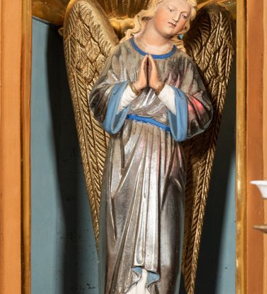 Zdjęcie nr 61: Nastawa ołtarzowa architektoniczna, jednoosiowa, jednokondygnacyjna z bramkami i zwieńczeniem, ustawiona na wysokim, dwustrefowym cokole. Ołtarz prostopadłościenny, murowany, umieszczony w drewnianej obudowie. Antependium ujęte ramą dekorowaną plecionką, podzielone na trzy pola: w środkowym płaskorzeźbione przedstawienie Ostatniej Wieczerzy według Leonarda da Vinci, a po bokach ornament roślinny o wertykalnym układzie.

Tabernakulum architektoniczne, jednokondygnacyjne, trójosiowe, ustawione na zdwojonym na cokole z dwoma zwieńczeniami na osiach skrajnych. Osie wydzielone są parami kolumn o kapitelach kompozytowych, oś środkowa wysunięta do przodu. Podpory dźwigają pełne belkowanie wyłamane na ich linii, przerwane nad polem środkowym, gdzie kolumny dźwigają przerwany półkolisty przyczółek połączony z łukiem gzymsu, nad nim ustawiona jest rzeźba Baranka leżącego na księdze z siedmioma pieczęciami. W polu środkowym dwuskrzydłowe drzwiczki do metalowego tabernakulum ujęte ramą w formie stojącego prostokąta, zamkniętego łukiem nadwieszonym z długim uskokiem. Na drzwiczkach znajdują się dwa aplikowane klęczące anioły, powyżej Chrismo w medalionie, otoczonym glorią. W osiach bocznych są nisze zamknięte konchami z figurkami aniołów, zamknięte zwieńczeniami w formie stojących prostokątów z falistym gzymsem i gałązkami lilii na szczycie; w polu srebrzone, owalne medaliony. Po bokach kondygnacji na wolutowych uszach oraz po bokach zwieńczeń znajdują się wazony ze słonecznikami. Cokół zdobiony jest ornamentem akantowym.

Kondygnacja ujęta jest dwiema parami kolumn o kapitelach kompozytowych oraz stojącą między nimi parą filarów. Podpory dźwigają pełne belkowanie o silnie wysuniętym gzymsie, wyłamane na osiach bocznych, z podwieszonymi szyszkami na tle filarów; przerwane nad polem środkowym. W centrum pole w formie stojącego prostokąta ujęte ramą dekorowaną ornamentem roślinnym z płaskorzeźbionym przedstawieniem Matki Boskiej z Dzieciątkiem. Na zasuwie obrazy: „Najświętsze Serce Pana Jezusa”, „Zwiastowanie” oraz „Św. Mikołaj”. Nad bramkami oraz pomiędzy kolumnami ustawione są rzeźby. Od lewej kolejno: św. Andrzej, św. Wojciech, św. Stanisław i na końcu po prawej św. Tomasz. Nad polem głównym znajduje się przeszklony prześwit w formie półkola z rzeźbioną gołębicą Ducha Świętego na tle glorii. Powyżej pole zamknięte półkoliście fragmentem gzymsu z rzeźbionym popiersiem błogosławiącego Boga Ojca pośród obłoków. Zwieńczenie w formie zbliżonej do stojącego prostokąta o wklęsłych bokach z gzymsem i z podwieszonym lambrekinem oraz kotarami spływającymi na boki. W polu przeszklony prześwit w formie kwadratu zamkniętego łukiem nadwieszonym z rzeźbionym monogramem Marii na tle glorii. Po bokach zwieńczenia ustawione są dwie duże figury klęczących aniołów.

Bramki po bokach ołtarza ustawione są na wysokości cokołu nastawy; przejścia ujęte są parą kanelowanych pilastrów, zamknięte łukiem utworzonym z dwóch przeciwstawnych wolut wspierających wieńczące cokoły. Przejścia w formie wydłużonego stojącego prostokąta zamkniętego łukiem półkolistym nadwieszonym.

Całość ołtarza oprócz tabernakulum dekorowana jest ornamentem małżowinowo-chrząstkowym. Uszy flankujące kondygnację utworzone są również z ornamentu małżowinowo-chrząstkowego. Na zamknięciu zwieńczenia znajdują się dwie uskrzydlone główki anielskie skierowane na wprost z podwieszonymi u szyi chustami. Struktura ołtarza polichromowana jest w kolorze brązowym ze złoconymi kolumnami, ornamentyką i profilami, detale srebrzone.