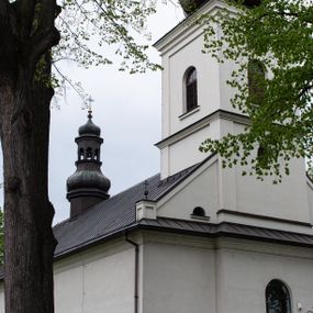 Zdjęcie nr 1: Kościół usytuowany jest w południowo-wschodniej części wsi, otoczony kamiennym murem, otynkowanym, krytym betonową płytą, w który wbudowano współczesne stacje drogi krzyżowej. Na plac kościelny prowadzą trzy bramy. Główna brama znajduje się w murze od strony zachodniej, nakryta jest ostrołukową arkadą. Dwie mniejsze bramy zlokalizowane są od strony południowej oraz od strony wschodniej. Na placu przed kościołem stoi pomnik z 1911 roku wystawiony na pamiątkę księdza Wojciecha Blaszyńskiego i działacza ludowego Stanisława Stojałowskiego. 
Świątynia jest orientowana, murowana, jednonawowa z węższym i krótkim prezbiterium, zamkniętym półkoliście oraz z wieżą na zakończeniu nawy. Do prezbiterium przylega zakrystia od północy i skarbczyk od południa. Od strony południowej dobudowana jest również niska kruchta. Wnętrze trójprzęsłowej nawy rozczłonkowane jest filarami przyściennymi wspierającymi sklepienie żagielkowe. Chór muzyczny trójarkadowy, wsparty na dwóch filarach. W ścianach korpusu nawowego znajdują się głębokie wnęki, w których umieszczone są prostokątne otwory okienne zamknięte półkolistym łukiem, po trzy od strony północnej i południowej; takie same okno znajduje się również w apsydzie od strony południowej oraz na chórze od strony zachodniej. Ponadto w apsydzie na wysokości zwieńczenia ołtarza głównego umieszczone jest małe, okrągłe okno. W kruchcie, skarbczyku i zakrystii okna są prostokątne. Drzwi główne dwuskrzydłowe, drewniane z metalowymi okuciami, zabezpieczone od wewnątrz dwiema żelaznymi zaporami umocowanymi w murze. Podobne drzwi znajdują się od strony południowej z kruchty. 
Fasada kościoła jest płaska, zakończona gzymsem z wysuniętą do przodu trójkondygnacyjną wieżą, nakrytą baniastym hełmem z latarnią. Drugie piętro wieży połączone jest z fasadą prostymi spływami. Przy wejściu na wysokich cokołach ustawione są rzeźby świętych Piotra i Pawła. 
Kościoł nakryty jest dachem dwuspadowym, na skrzyżowaniu nawy z prezbiterium umieszczona jest sygnaturka z hełmem baniastym z latarnią. 
