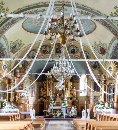 Zdjęcie nr 17: Kościół usytuowany jest w południowo-wschodniej części wsi, otoczony kamiennym murem, otynkowanym, krytym betonową płytą, w który wbudowano współczesne stacje drogi krzyżowej. Na plac kościelny prowadzą trzy bramy. Główna brama znajduje się w murze od strony zachodniej, nakryta jest ostrołukową arkadą. Dwie mniejsze bramy zlokalizowane są od strony południowej oraz od strony wschodniej. Na placu przed kościołem stoi pomnik z 1911 roku wystawiony na pamiątkę księdza Wojciecha Blaszyńskiego i działacza ludowego Stanisława Stojałowskiego. 
Świątynia jest orientowana, murowana, jednonawowa z węższym i krótkim prezbiterium, zamkniętym półkoliście oraz z wieżą na zakończeniu nawy. Do prezbiterium przylega zakrystia od północy i skarbczyk od południa. Od strony południowej dobudowana jest również niska kruchta. Wnętrze trójprzęsłowej nawy rozczłonkowane jest filarami przyściennymi wspierającymi sklepienie żagielkowe. Chór muzyczny trójarkadowy, wsparty na dwóch filarach. W ścianach korpusu nawowego znajdują się głębokie wnęki, w których umieszczone są prostokątne otwory okienne zamknięte półkolistym łukiem, po trzy od strony północnej i południowej; takie same okno znajduje się również w apsydzie od strony południowej oraz na chórze od strony zachodniej. Ponadto w apsydzie na wysokości zwieńczenia ołtarza głównego umieszczone jest małe, okrągłe okno. W kruchcie, skarbczyku i zakrystii okna są prostokątne. Drzwi główne dwuskrzydłowe, drewniane z metalowymi okuciami, zabezpieczone od wewnątrz dwiema żelaznymi zaporami umocowanymi w murze. Podobne drzwi znajdują się od strony południowej z kruchty. 
Fasada kościoła jest płaska, zakończona gzymsem z wysuniętą do przodu trójkondygnacyjną wieżą, nakrytą baniastym hełmem z latarnią. Drugie piętro wieży połączone jest z fasadą prostymi spływami. Przy wejściu na wysokich cokołach ustawione są rzeźby świętych Piotra i Pawła. 
Kościoł nakryty jest dachem dwuspadowym, na skrzyżowaniu nawy z prezbiterium umieszczona jest sygnaturka z hełmem baniastym z latarnią. 
