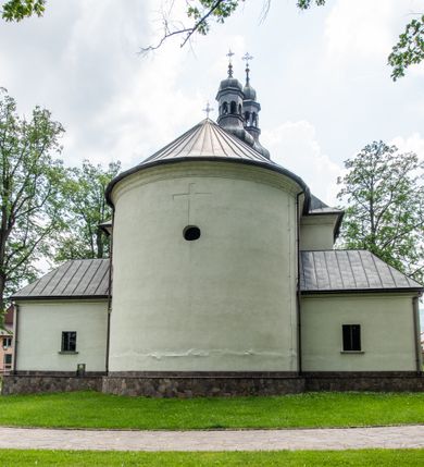Zdjęcie nr 12: Kościół usytuowany jest w południowo-wschodniej części wsi, otoczony kamiennym murem, otynkowanym, krytym betonową płytą, w który wbudowano współczesne stacje drogi krzyżowej. Na plac kościelny prowadzą trzy bramy. Główna brama znajduje się w murze od strony zachodniej, nakryta jest ostrołukową arkadą. Dwie mniejsze bramy zlokalizowane są od strony południowej oraz od strony wschodniej. Na placu przed kościołem stoi pomnik z 1911 roku wystawiony na pamiątkę księdza Wojciecha Blaszyńskiego i działacza ludowego Stanisława Stojałowskiego. 
Świątynia jest orientowana, murowana, jednonawowa z węższym i krótkim prezbiterium, zamkniętym półkoliście oraz z wieżą na zakończeniu nawy. Do prezbiterium przylega zakrystia od północy i skarbczyk od południa. Od strony południowej dobudowana jest również niska kruchta. Wnętrze trójprzęsłowej nawy rozczłonkowane jest filarami przyściennymi wspierającymi sklepienie żagielkowe. Chór muzyczny trójarkadowy, wsparty na dwóch filarach. W ścianach korpusu nawowego znajdują się głębokie wnęki, w których umieszczone są prostokątne otwory okienne zamknięte półkolistym łukiem, po trzy od strony północnej i południowej; takie same okno znajduje się również w apsydzie od strony południowej oraz na chórze od strony zachodniej. Ponadto w apsydzie na wysokości zwieńczenia ołtarza głównego umieszczone jest małe, okrągłe okno. W kruchcie, skarbczyku i zakrystii okna są prostokątne. Drzwi główne dwuskrzydłowe, drewniane z metalowymi okuciami, zabezpieczone od wewnątrz dwiema żelaznymi zaporami umocowanymi w murze. Podobne drzwi znajdują się od strony południowej z kruchty. 
Fasada kościoła jest płaska, zakończona gzymsem z wysuniętą do przodu trójkondygnacyjną wieżą, nakrytą baniastym hełmem z latarnią. Drugie piętro wieży połączone jest z fasadą prostymi spływami. Przy wejściu na wysokich cokołach ustawione są rzeźby świętych Piotra i Pawła. 
Kościoł nakryty jest dachem dwuspadowym, na skrzyżowaniu nawy z prezbiterium umieszczona jest sygnaturka z hełmem baniastym z latarnią. 

