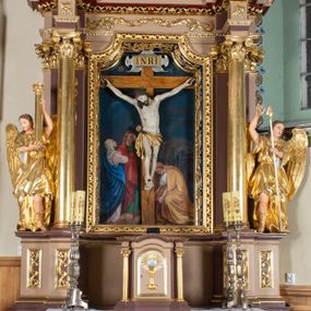 Zdjęcie nr 1: Nastawa ołtarzowa architektoniczna, jednoosiowa i jednokondygnacyjna. Ołtarz prostopadłościenny, drewniany, z drewnianą mensą i z marmurowym portatylem. Antepedium w formie prostokąta ujętego profilowaną ramą. W polu płycina o narożach zdobionych płaskorzeźbioną dekoracją roślinną złożoną z liści stylizowanego akantu oraz umieszczonym w polu veraikonem na tle obłoków i w promienistej glorii. Tabernakulum w kształcie prostopadłościennej skrzynki na niskim cokole, flankowane dwiema kolumnami ustawionymi pod kątem, zamknięte od góry prostym belkowaniem, pośrodku nadwieszonym. Na drzwiczkach płycina w kształcie stojącego prostokąta, zamkniętego łukiem półkolistym, ujęta profilowaną ramą, w polu której umieszczony jest płaskorzeźbiony kielich z hostią.

Retabulum ustawione na podwójnym cokole, flankowane parą zdwojonych pilastrów i ustawionych przed nimi dwiema kolumnami. Podpory dźwigają wyłamane na osi belkowanie z ustawionymi na bokach rzeźbami aniołków z arma Christi (włóczniami). Kolumny wspierają się na bazach, trzony mają gładkie i złocone, a kapitele kompozytowe. Po bokach ołtarza na niskich cokołach ustawione są rzeźby aniołów z narzędziami męki Pańskiej w dłoniach: kolumną biczowania po lewej stronie i włócznią po prawej stronie. W polu, w głębokiej wnęce ujętej szeroką, profilowaną ramą umieszczony jest późnobarokowy krucyfiks na tle malowanej Golgoty i postaci Matki Boskiej, św. Jana Ewangelisty i św. Weroniki. Wnęka od wewnątrz zdobiona jest płaskorzeźbioną winną latoroślą. Cokół dekorowany jest prostokątnymi po bokach płycinami, wypełnionymi stylizowanym akantem. Belkowanie zdobione wicią liści akantu, imposty rozetkami. W zwieńczeniu monumentalna promienista gloria złożona z wiązek promieni o nierównej długości z monogramem Chrystusa na niebieskim tle w polu, otoczonym wieńcem z obłoków. Struktura polichromowana w kolorze jasnego, delikatnego fioletu, płyciny, filary i detale w odcieniu delikatnie ciemniejszym; ornamentyka i profilowania złocone i srebrzone.


