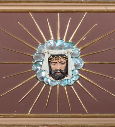 Zdjęcie nr 49: Nastawa ołtarzowa architektoniczna, jednoosiowa i jednokondygnacyjna. Ołtarz prostopadłościenny, drewniany, z drewnianą mensą i z marmurowym portatylem. Antepedium w formie prostokąta ujętego profilowaną ramą. W polu płycina o narożach zdobionych płaskorzeźbioną dekoracją roślinną złożoną z liści stylizowanego akantu oraz umieszczonym w polu veraikonem na tle obłoków i w promienistej glorii. Tabernakulum w kształcie prostopadłościennej skrzynki na niskim cokole, flankowane dwiema kolumnami ustawionymi pod kątem, zamknięte od góry prostym belkowaniem, pośrodku nadwieszonym. Na drzwiczkach płycina w kształcie stojącego prostokąta, zamkniętego łukiem półkolistym, ujęta profilowaną ramą, w polu której umieszczony jest płaskorzeźbiony kielich z hostią.

Retabulum ustawione na podwójnym cokole, flankowane parą zdwojonych pilastrów i ustawionych przed nimi dwiema kolumnami. Podpory dźwigają wyłamane na osi belkowanie z ustawionymi na bokach rzeźbami aniołków z arma Christi (włóczniami). Kolumny wspierają się na bazach, trzony mają gładkie i złocone, a kapitele kompozytowe. Po bokach ołtarza na niskich cokołach ustawione są rzeźby aniołów z narzędziami męki Pańskiej w dłoniach: kolumną biczowania po lewej stronie i włócznią po prawej stronie. W polu, w głębokiej wnęce ujętej szeroką, profilowaną ramą umieszczony jest późnobarokowy krucyfiks na tle malowanej Golgoty i postaci Matki Boskiej, św. Jana Ewangelisty i św. Weroniki. Wnęka od wewnątrz zdobiona jest płaskorzeźbioną winną latoroślą. Cokół dekorowany jest prostokątnymi po bokach płycinami, wypełnionymi stylizowanym akantem. Belkowanie zdobione wicią liści akantu, imposty rozetkami. W zwieńczeniu monumentalna promienista gloria złożona z wiązek promieni o nierównej długości z monogramem Chrystusa na niebieskim tle w polu, otoczonym wieńcem z obłoków. Struktura polichromowana w kolorze jasnego, delikatnego fioletu, płyciny, filary i detale w odcieniu delikatnie ciemniejszym; ornamentyka i profilowania złocone i srebrzone.


