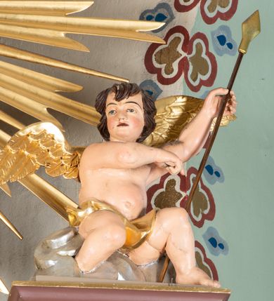 Zdjęcie nr 47: Nastawa ołtarzowa architektoniczna, jednoosiowa i jednokondygnacyjna. Ołtarz prostopadłościenny, drewniany, z drewnianą mensą i z marmurowym portatylem. Antepedium w formie prostokąta ujętego profilowaną ramą. W polu płycina o narożach zdobionych płaskorzeźbioną dekoracją roślinną złożoną z liści stylizowanego akantu oraz umieszczonym w polu veraikonem na tle obłoków i w promienistej glorii. Tabernakulum w kształcie prostopadłościennej skrzynki na niskim cokole, flankowane dwiema kolumnami ustawionymi pod kątem, zamknięte od góry prostym belkowaniem, pośrodku nadwieszonym. Na drzwiczkach płycina w kształcie stojącego prostokąta, zamkniętego łukiem półkolistym, ujęta profilowaną ramą, w polu której umieszczony jest płaskorzeźbiony kielich z hostią.

Retabulum ustawione na podwójnym cokole, flankowane parą zdwojonych pilastrów i ustawionych przed nimi dwiema kolumnami. Podpory dźwigają wyłamane na osi belkowanie z ustawionymi na bokach rzeźbami aniołków z arma Christi (włóczniami). Kolumny wspierają się na bazach, trzony mają gładkie i złocone, a kapitele kompozytowe. Po bokach ołtarza na niskich cokołach ustawione są rzeźby aniołów z narzędziami męki Pańskiej w dłoniach: kolumną biczowania po lewej stronie i włócznią po prawej stronie. W polu, w głębokiej wnęce ujętej szeroką, profilowaną ramą umieszczony jest późnobarokowy krucyfiks na tle malowanej Golgoty i postaci Matki Boskiej, św. Jana Ewangelisty i św. Weroniki. Wnęka od wewnątrz zdobiona jest płaskorzeźbioną winną latoroślą. Cokół dekorowany jest prostokątnymi po bokach płycinami, wypełnionymi stylizowanym akantem. Belkowanie zdobione wicią liści akantu, imposty rozetkami. W zwieńczeniu monumentalna promienista gloria złożona z wiązek promieni o nierównej długości z monogramem Chrystusa na niebieskim tle w polu, otoczonym wieńcem z obłoków. Struktura polichromowana w kolorze jasnego, delikatnego fioletu, płyciny, filary i detale w odcieniu delikatnie ciemniejszym; ornamentyka i profilowania złocone i srebrzone.


